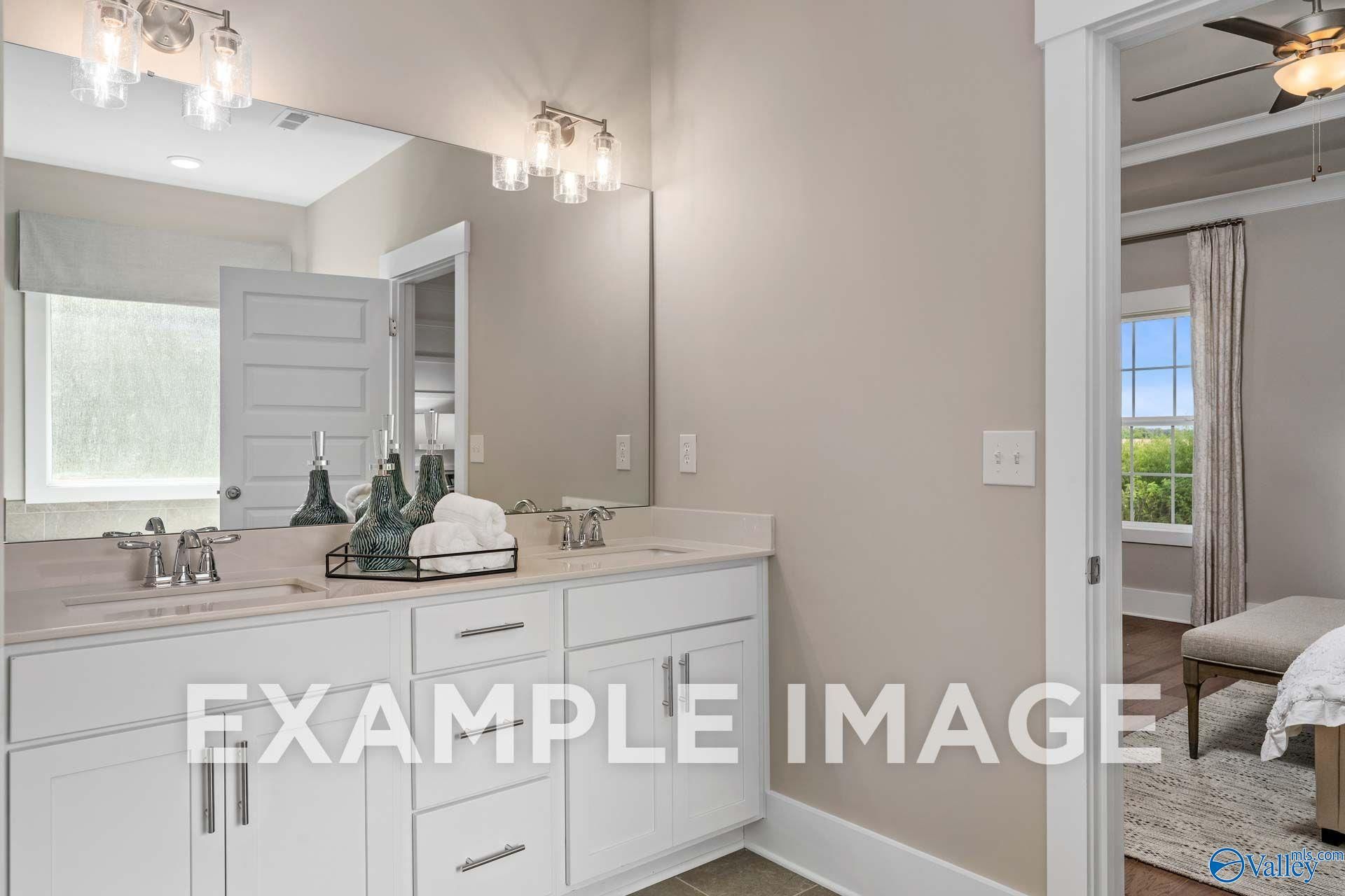 Dual vanity bathroom with white cabinetry and large mirror in The Harrison floor plan home by Davidson Homes, Hartselle, Alabama