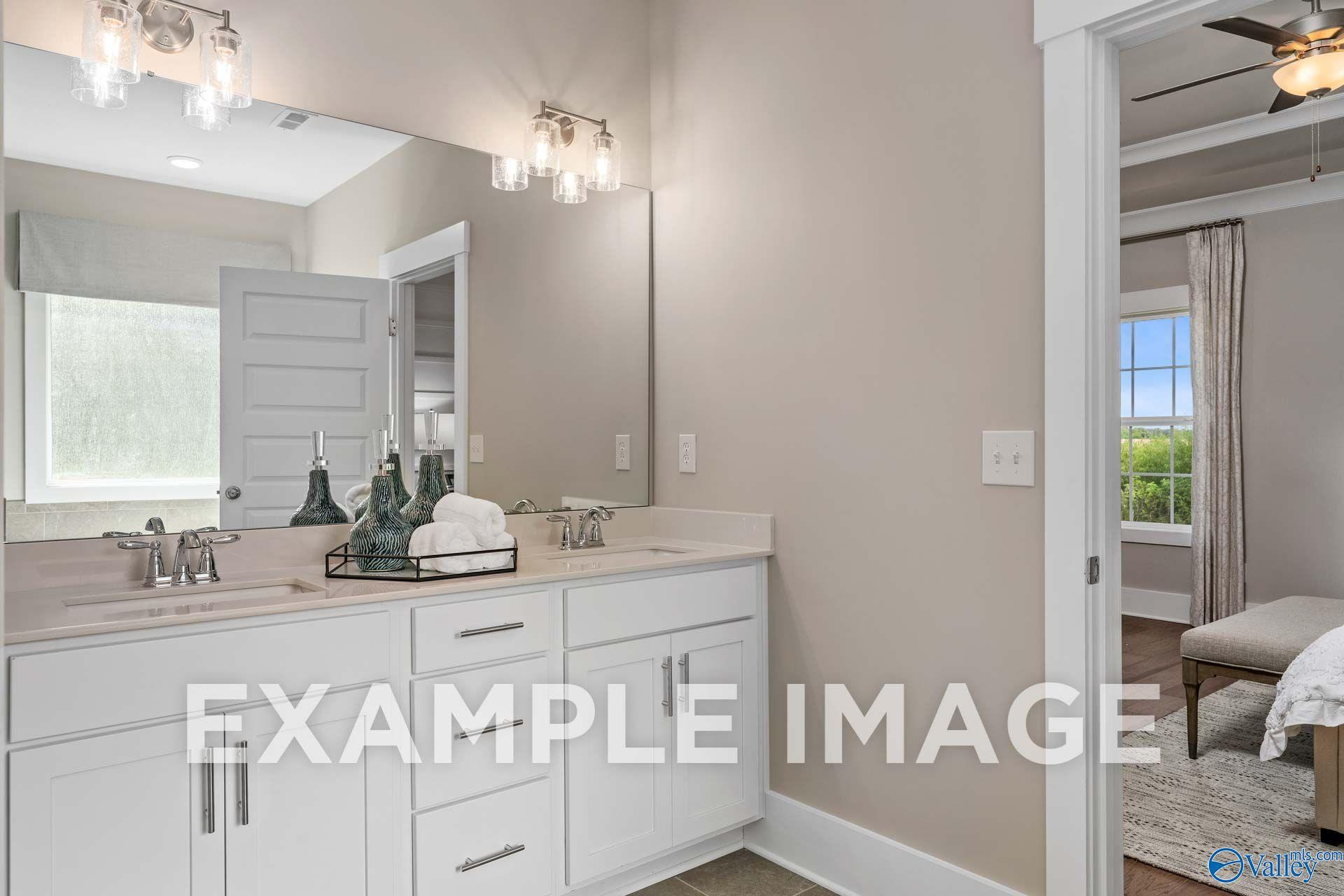 Dual vanity bathroom with white cabinetry and large mirror in The Harrison floor plan home by Davidson Homes, Hartselle, Alabama
