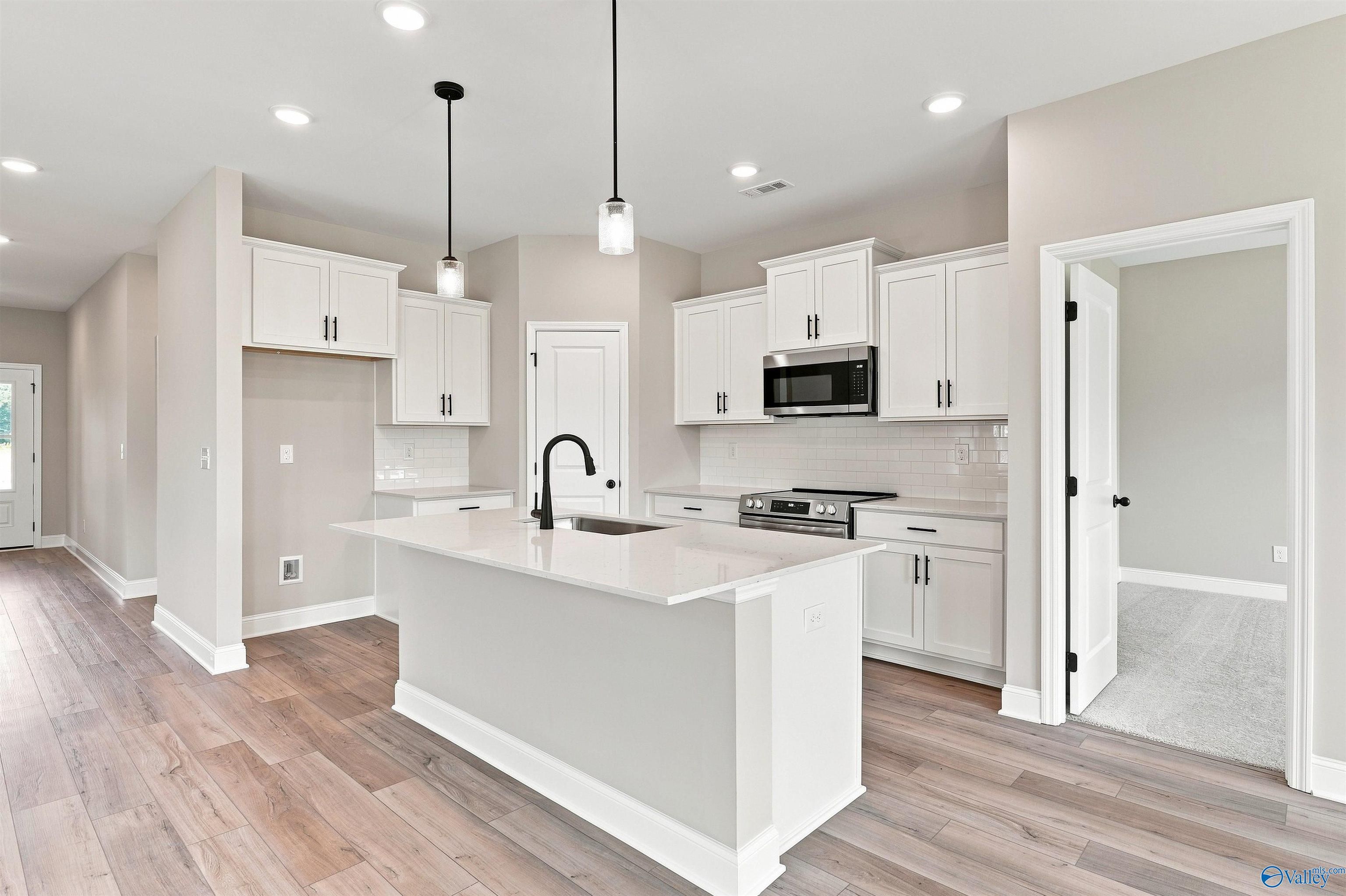 Modern white kitchen with island, pendant lights, and stainless appliances in Davidson Homes Franklin C plan, Toney, Alabama