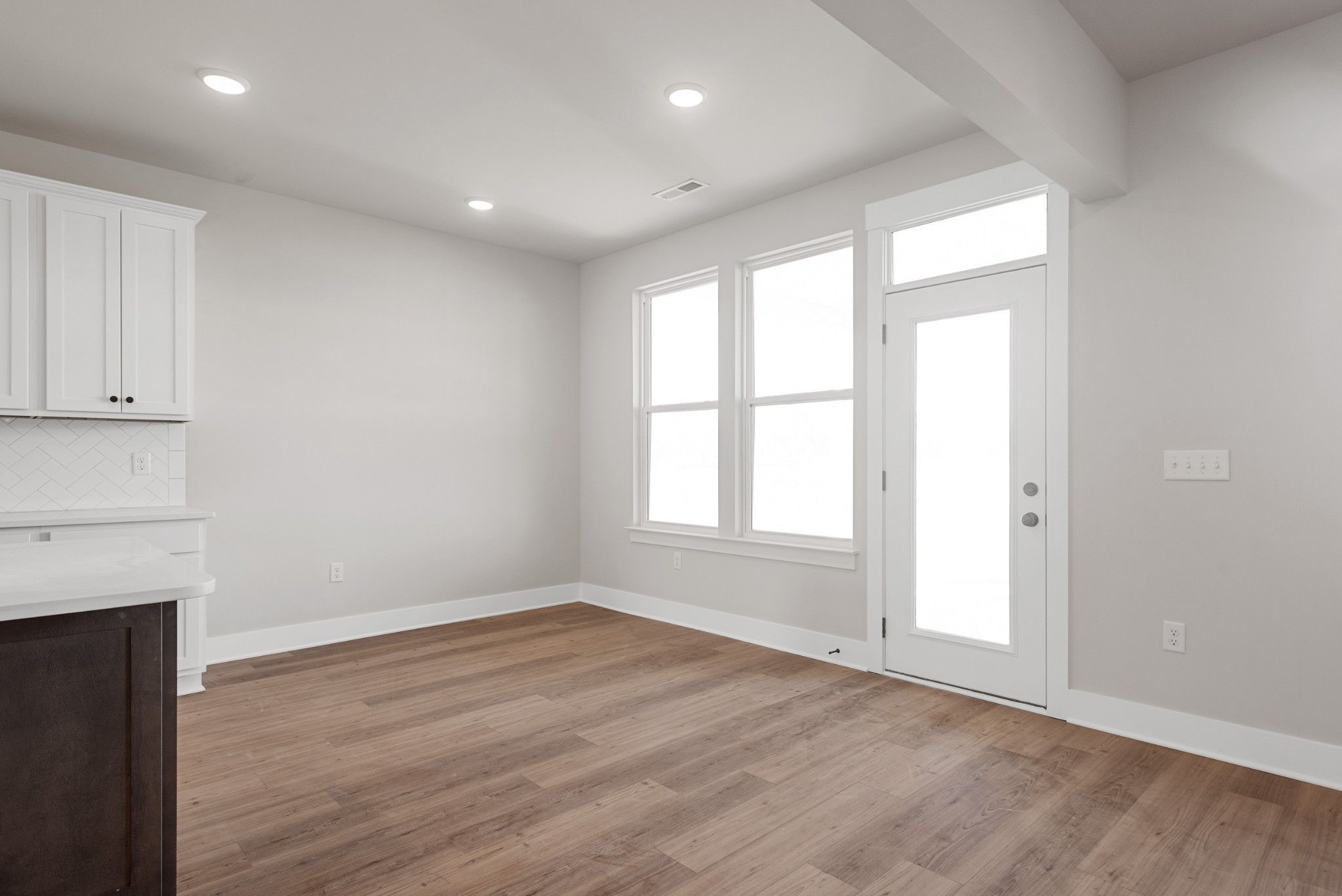 Bright kitchen with white shaker cabinets, quartz sink countertop, hardwood floors, and large windows in Davidson Homes The Willow B, White House TN