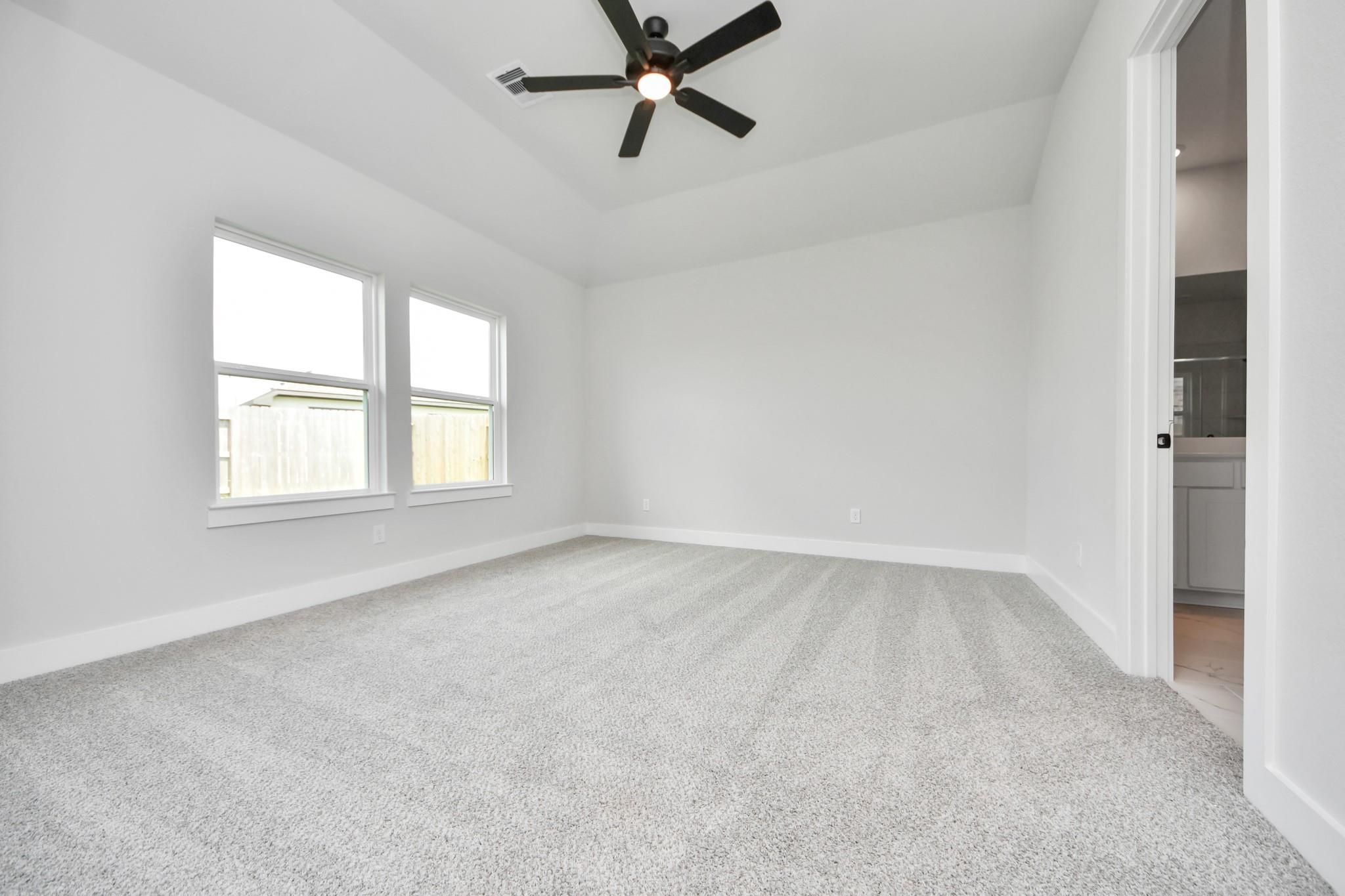 Spacious bedroom with tray ceiling and ceiling fan in The Laguna C floor plan by Davidson Homes in Sunterra, Katy, Texas.