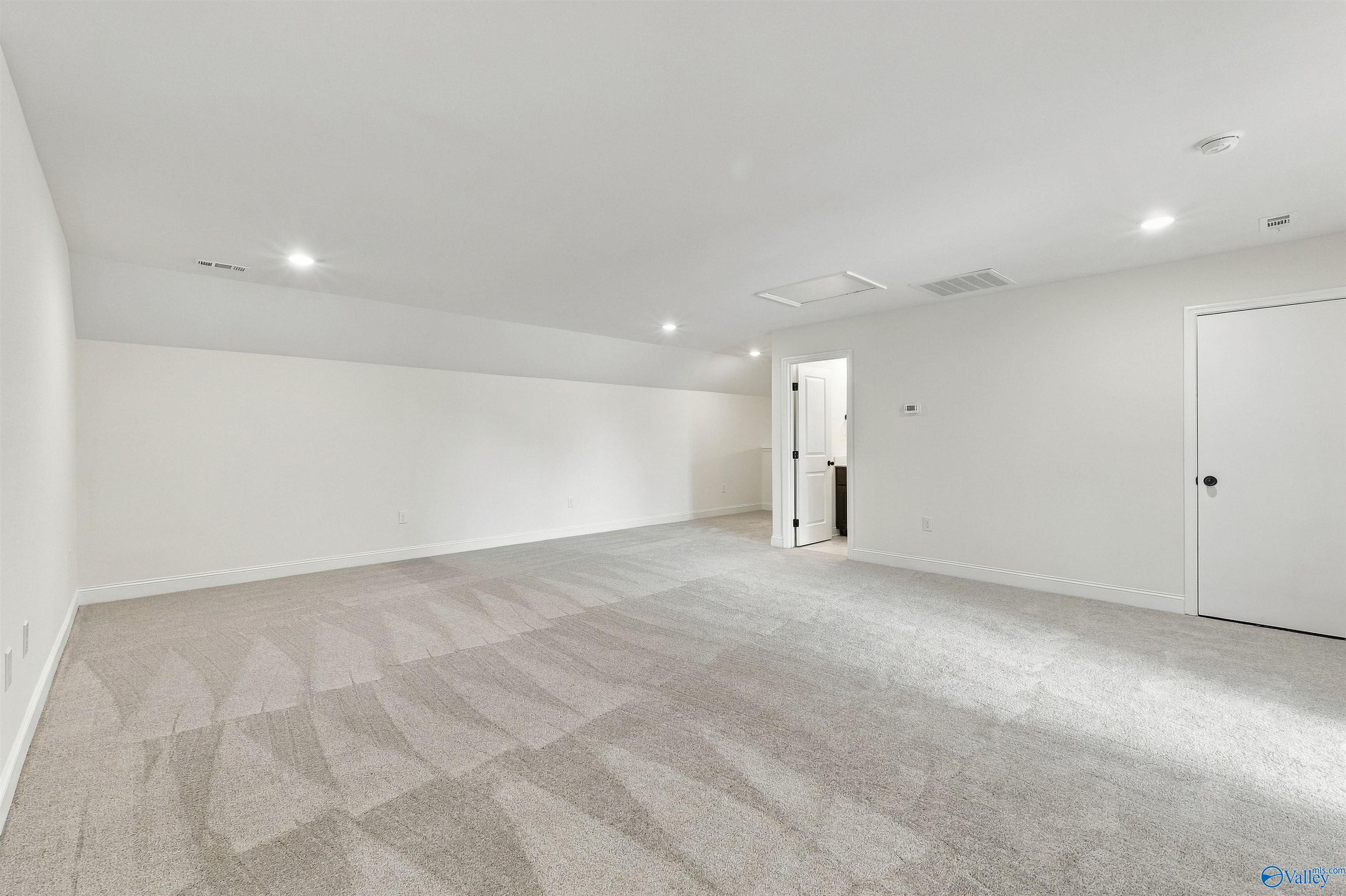 Spacious bonus room with vaulted ceiling, neutral carpet, and recessed lighting in Davidson Homes' The Valencia, Huntsville, Alabama