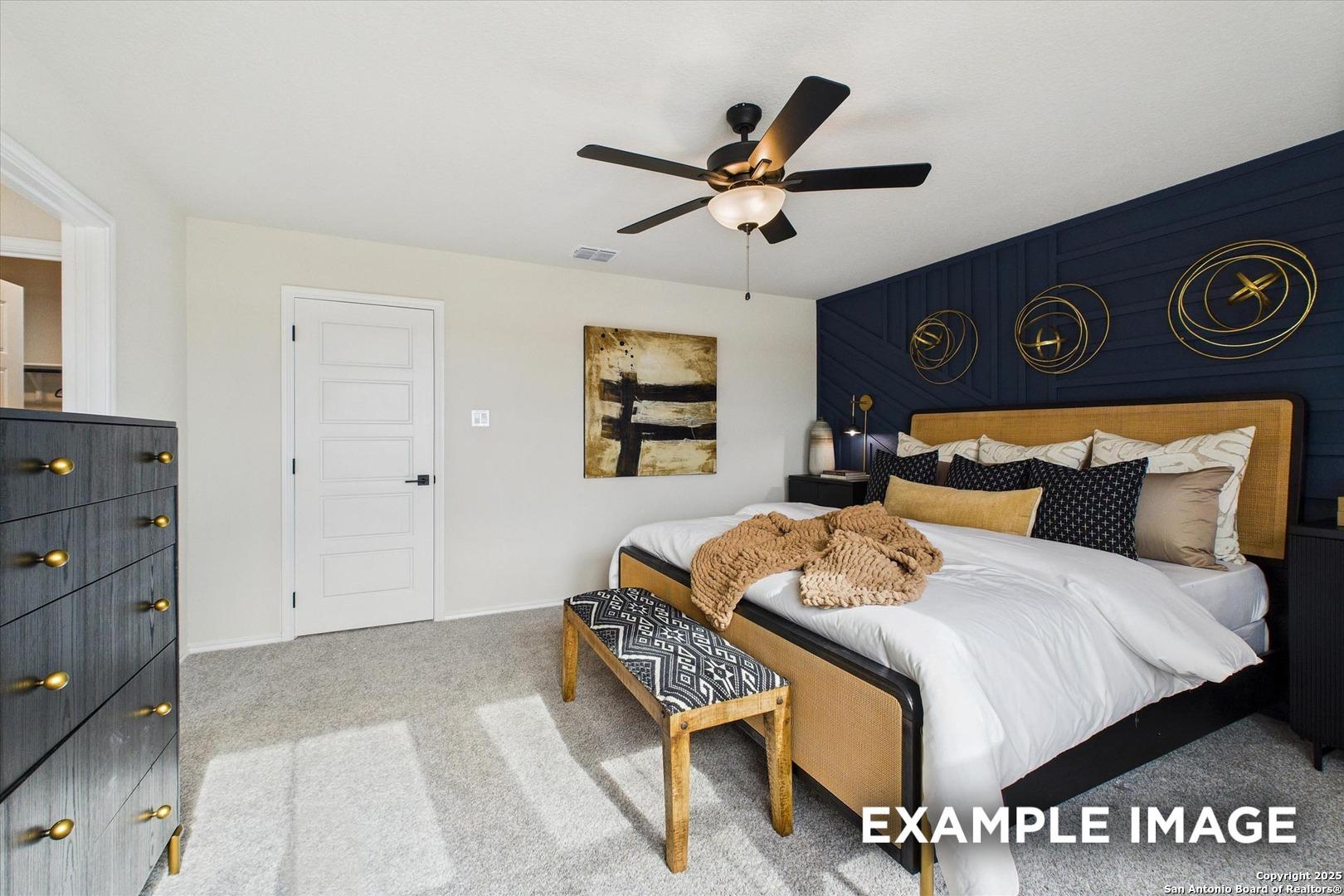 Elegant master bedroom with navy accent wall, king bed, gold metallic decor, and ceiling fan in Davidson Homes The Florence C, San Antonio, Texas