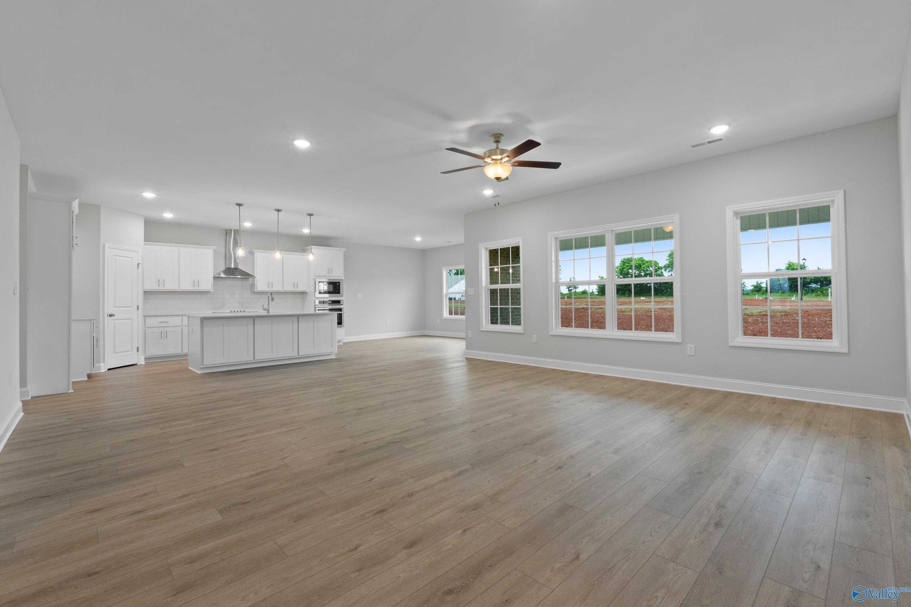 Spacious open living room with kitchen island, large windows, ceiling fan in Davidson Homes The Rockford B, Toney, AL