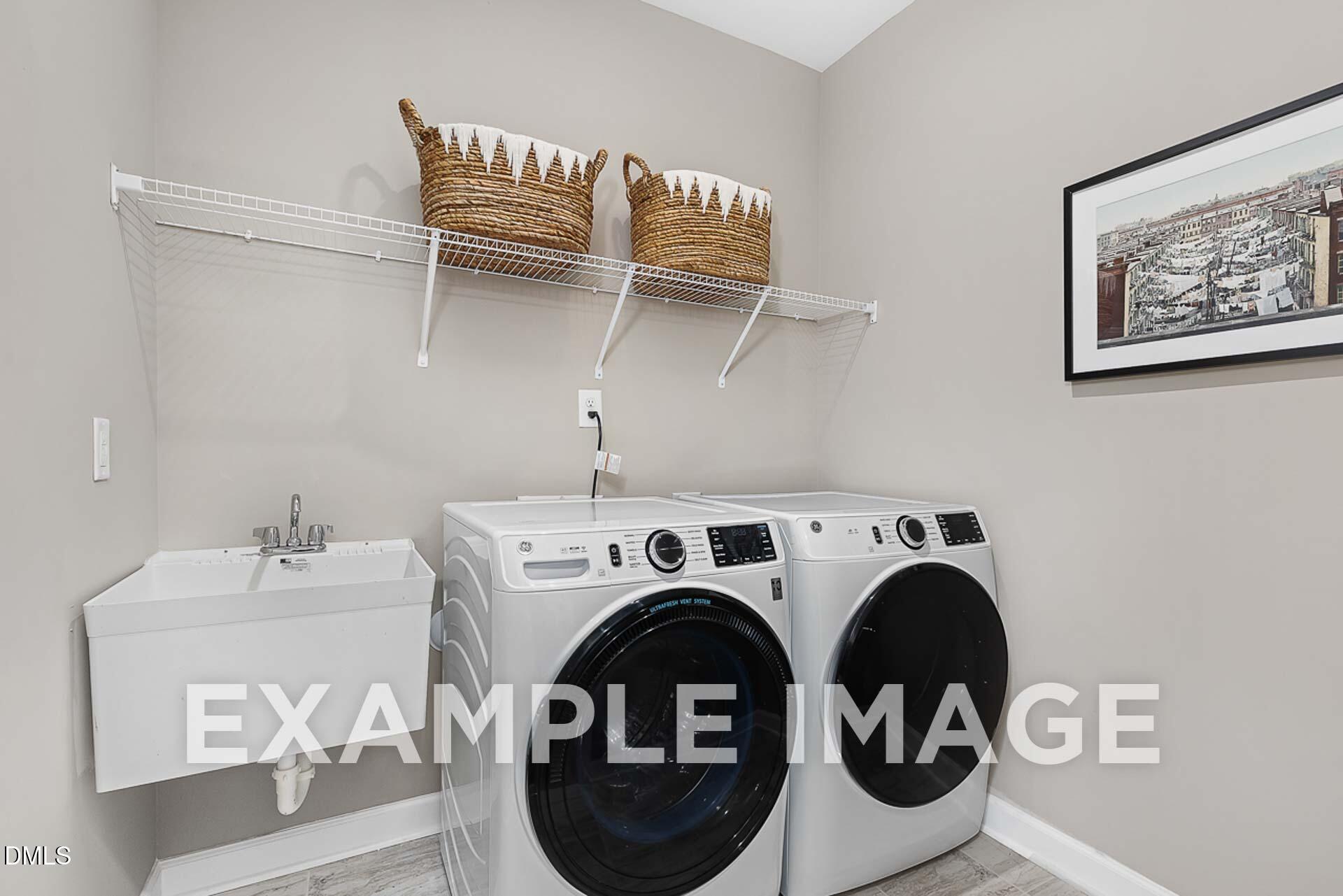 Modern laundry room with white front-load washer dryer, utility sink, wire shelves, and wicker baskets in Davidson Homes The Ash B, Lillington, NC