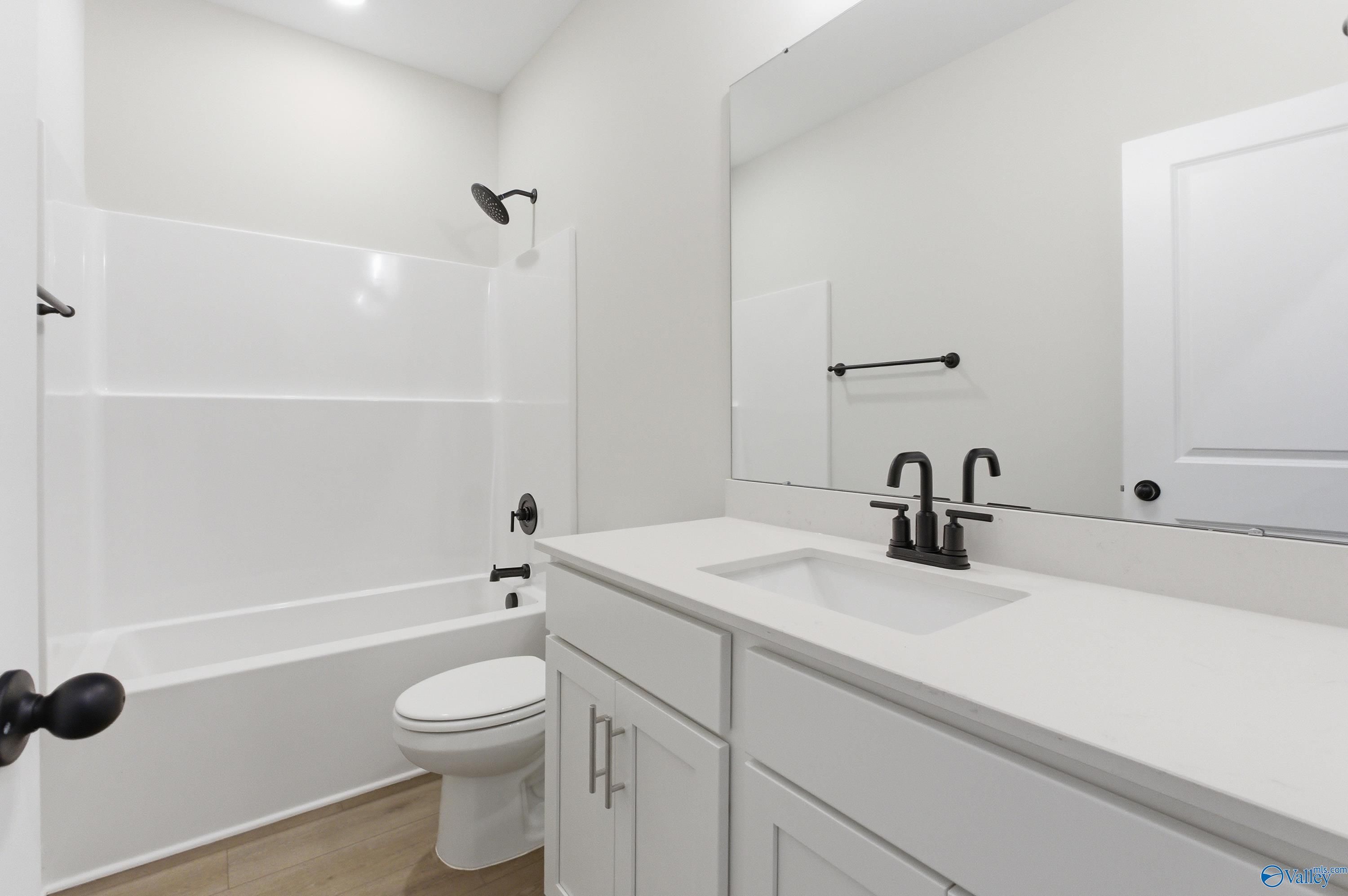 Modern white guest bathroom featuring bathtub, tiled shower, vanity sink, and black fixtures in Davidson Homes The Daphne C, Huntsville, AL