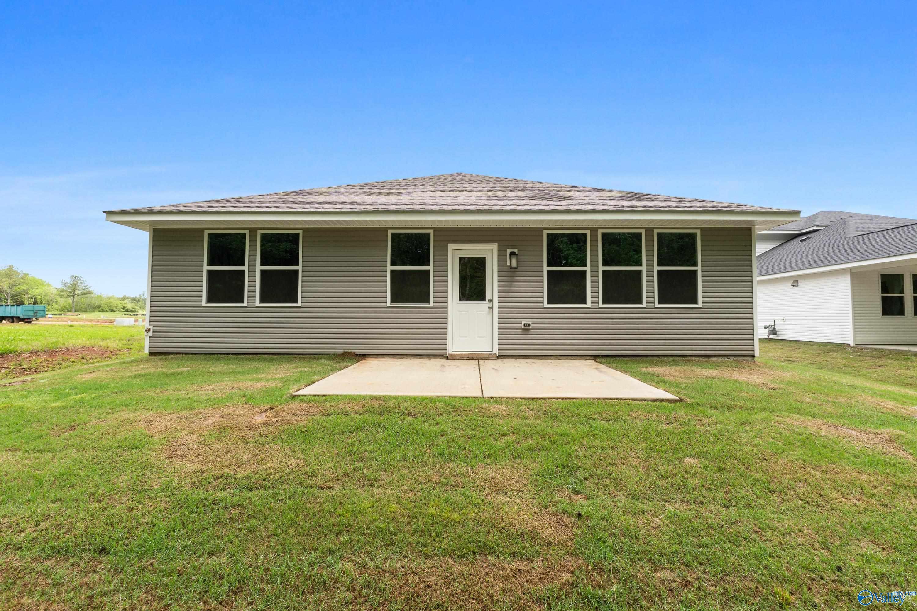 Rear view of The Luna 4-bedroom home by Davidson Homes in Forest Glen, Hazel Green, Alabama, featuring concrete patio and green yard