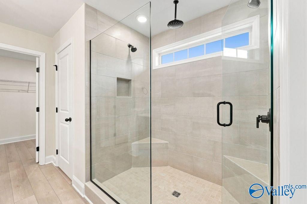 Walk-in tiled shower with glass door and built-in bench in The Madison A floor plan by Davidson Homes in Hartselle, Alabama.