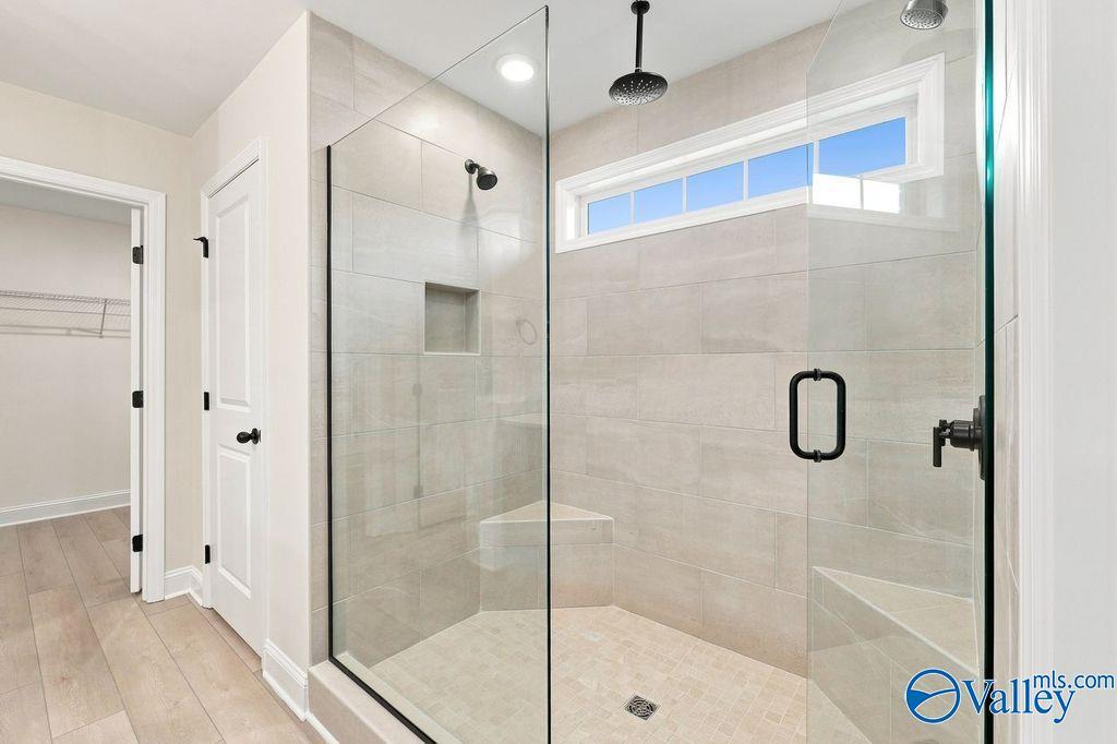 Walk-in tiled shower with glass door and built-in bench in The Madison A floor plan by Davidson Homes in Hartselle, Alabama.
