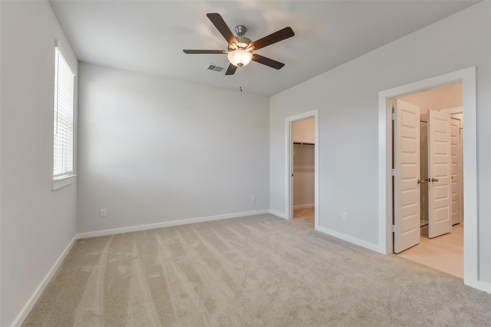 Spacious master bedroom with ceiling fan, walk-in closet doors, and en-suite access in Davidson Homes The Colorado F, Cleveland, Texas