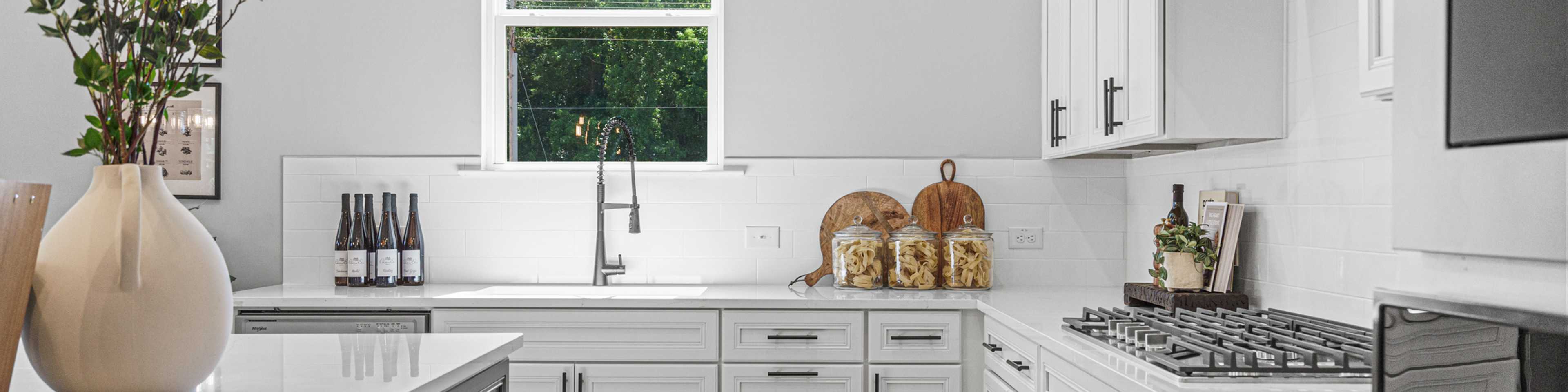 Spacious modern kitchen in Cedar Farms Winder GA with white shaker cabinets, dark quartz island, gas cooktop, and hardwood floors