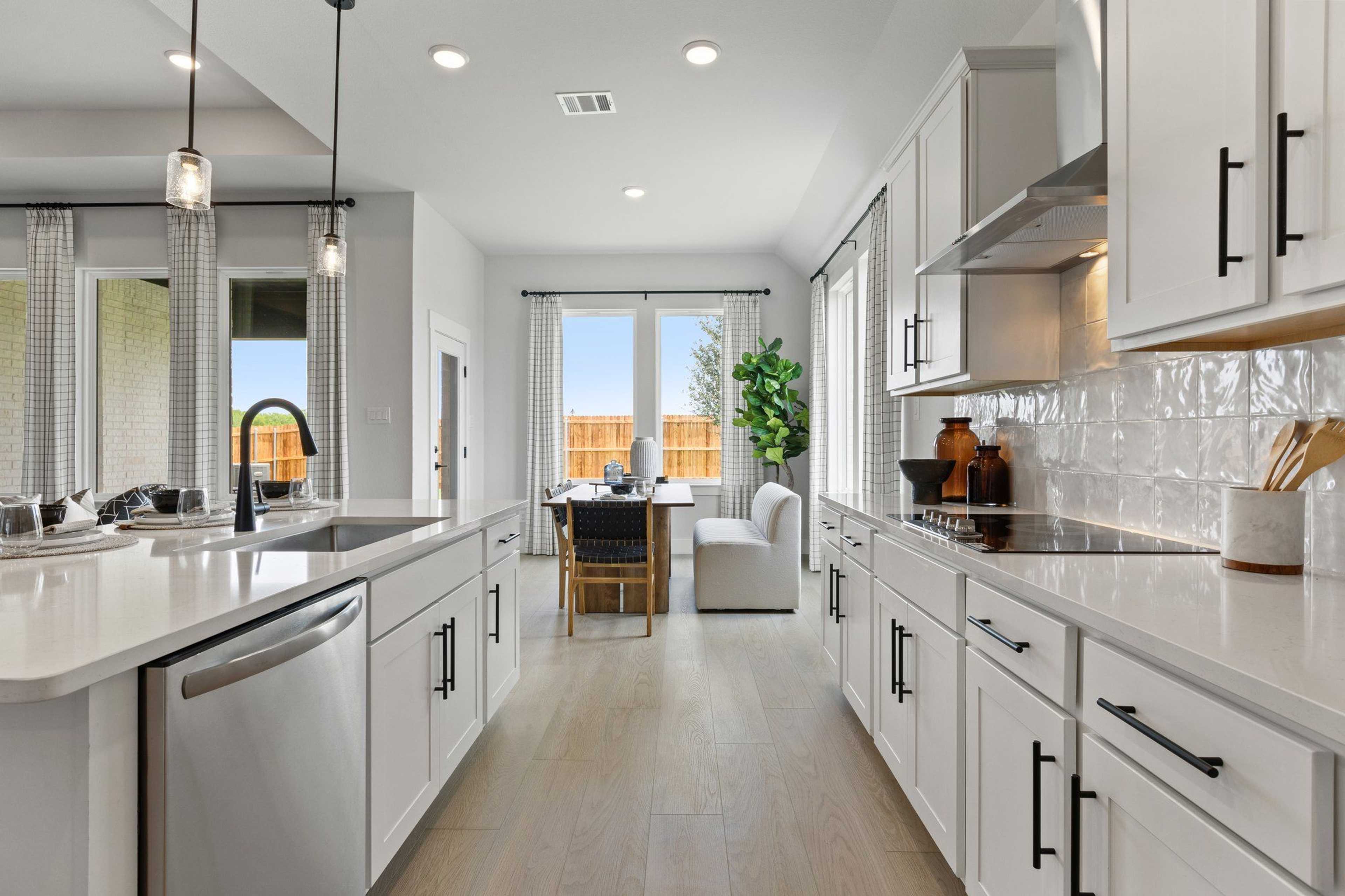 Modern open-concept kitchen and dining at Parks at Foster Crossing in Anna, Texas with white cabinets, quartz counters, and hardwood floors