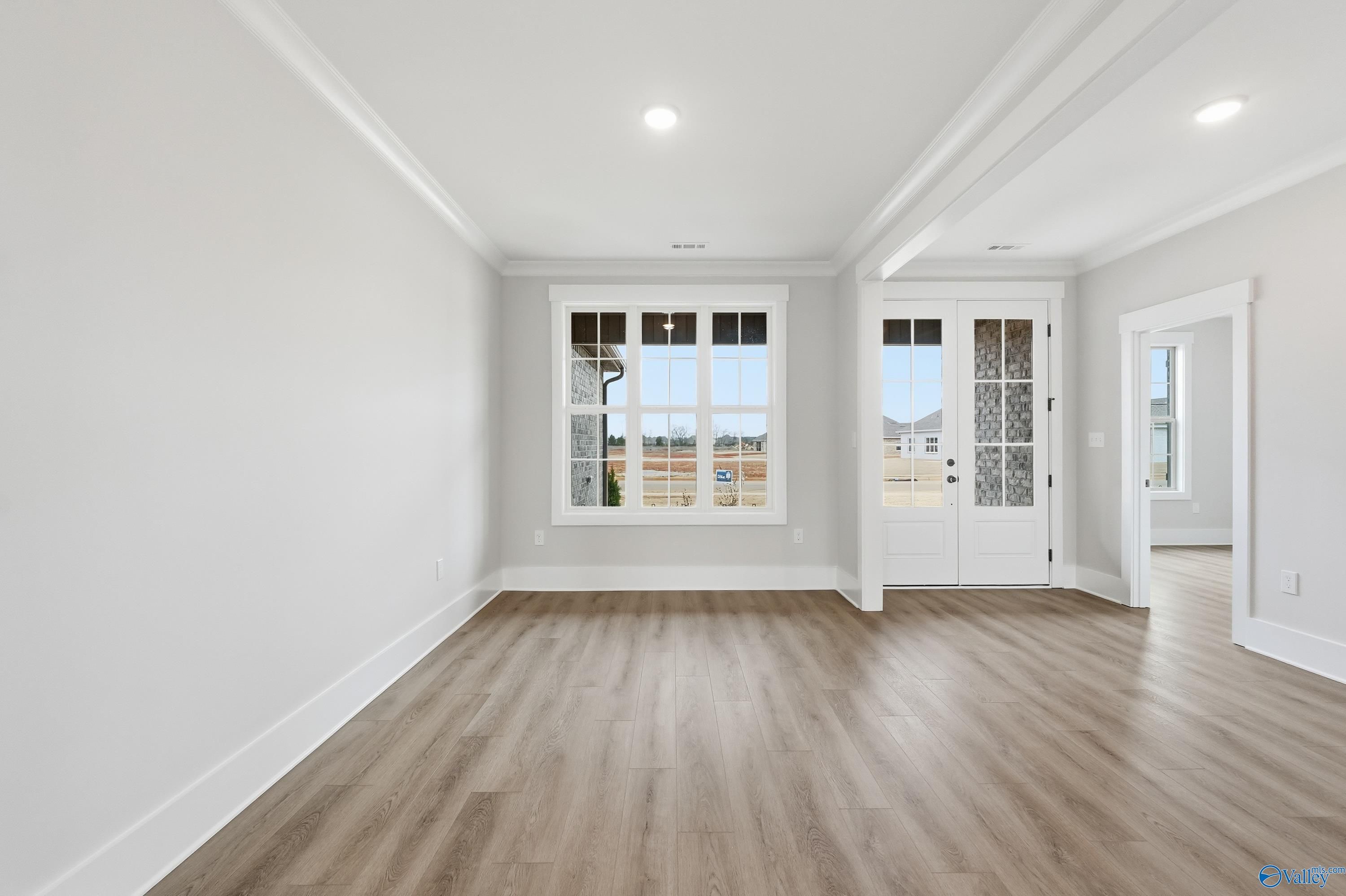 Bright living room with large windows, French doors to yard, white walls, and hardwood floors in The Finleigh home, Meridianville, Alabama