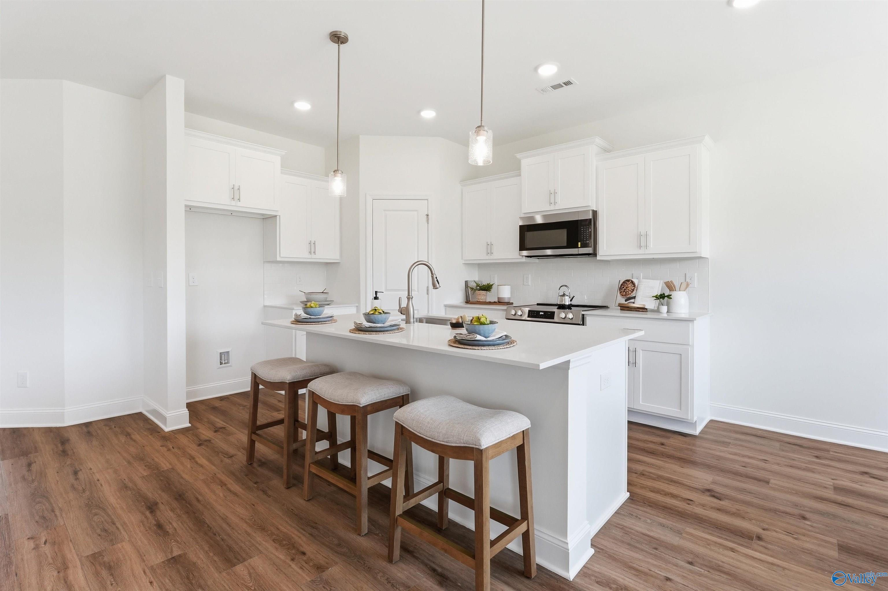 Modern kitchen with white cabinets, quartz island, and bar seating in The Franklin C floor plan, Lynn Meadows, Meridianville.