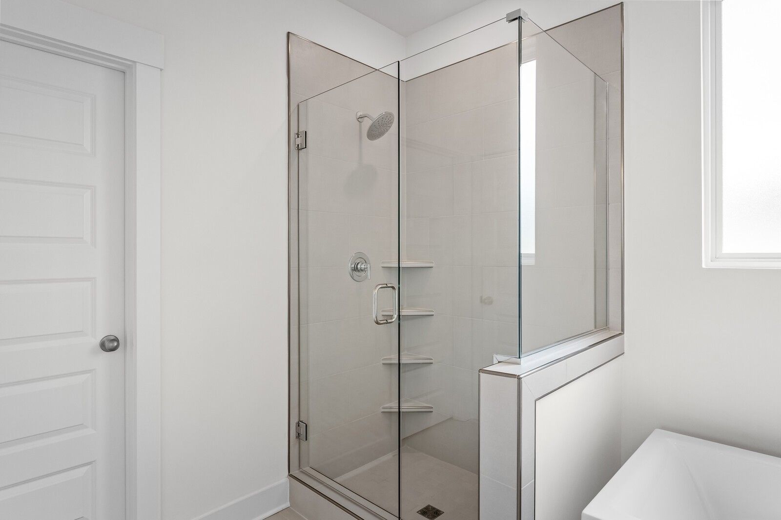 Modern frameless glass walk-in shower with rain showerhead and built-in shelves in master bathroom, Davidson Homes The Ridgeport, Gallatin TN