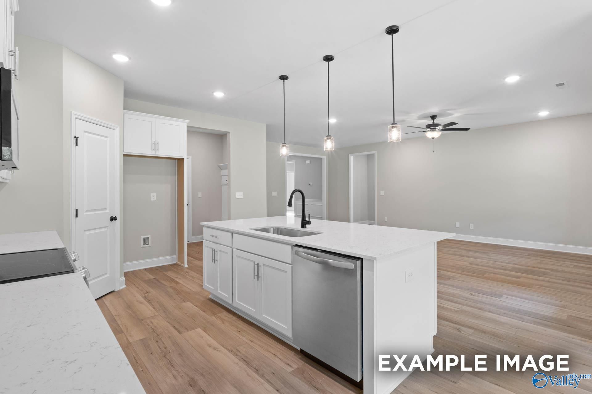 Modern white kitchen island with farmhouse sink, stainless dishwasher, and shaker cabinets in open-concept Davidson Homes The Montgomery B, Toney AL