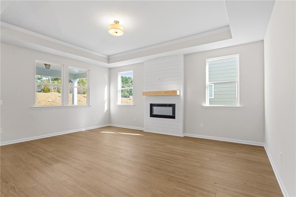 Spacious living room with white brick gas fireplace, large windows, hardwood floors in Davidson Homes The Edison B, Loganville, Georgia