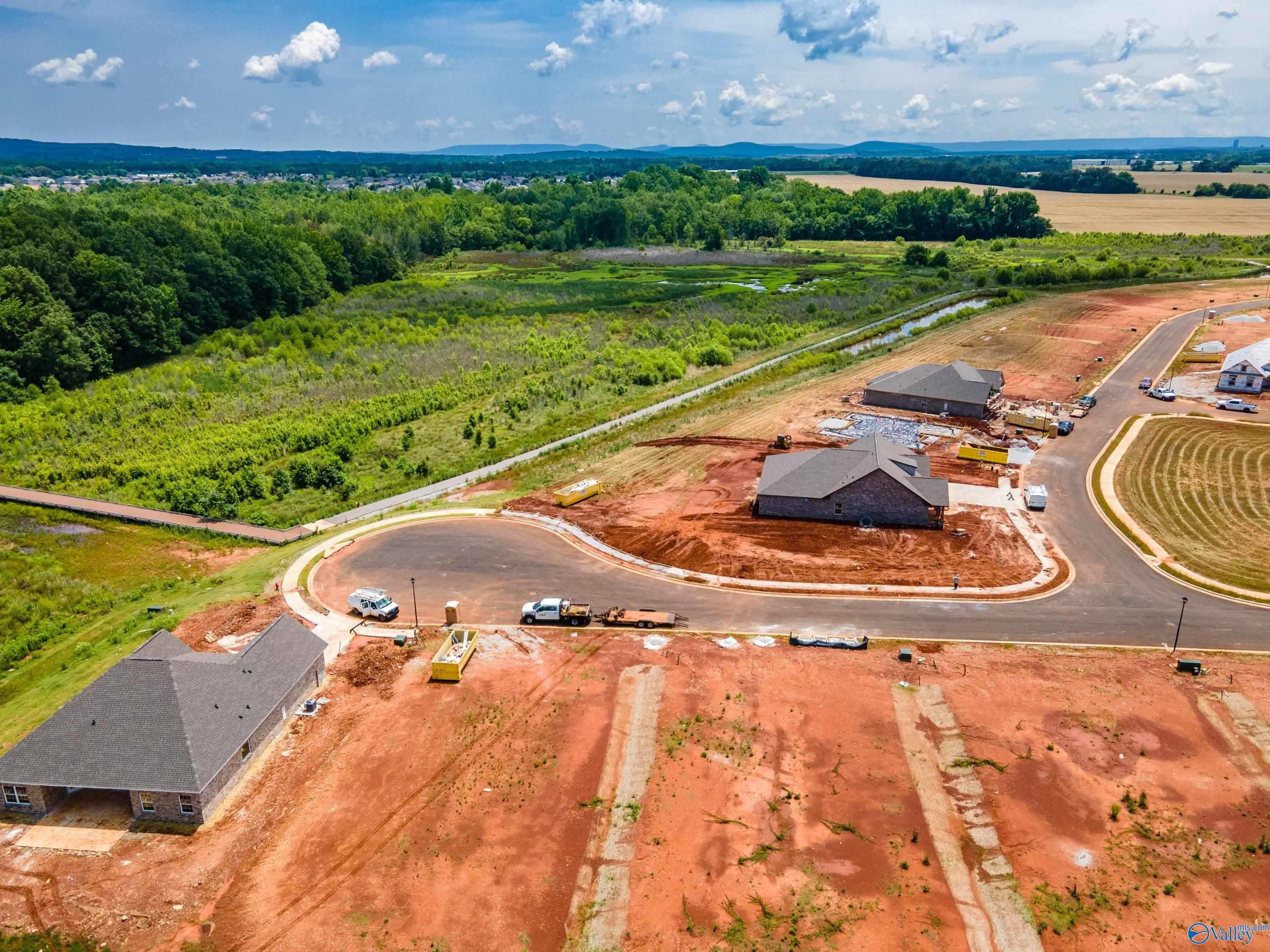 Aerial view of The Rockford with Bonus home construction in Barnett's Crossing, Madison, Alabama, with red dirt lots and wooded backdrop