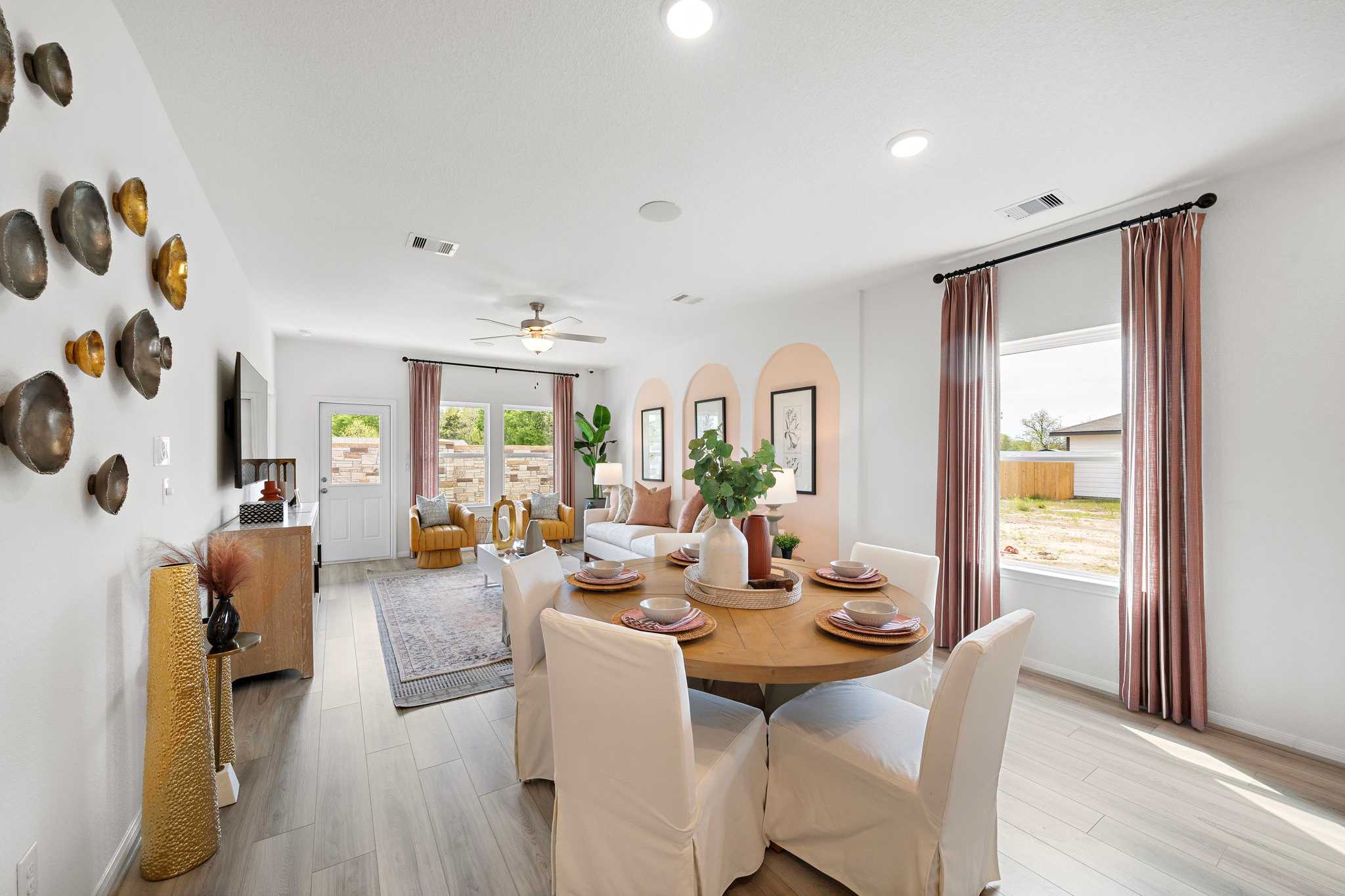 Spacious open-concept dining area in Davidson Homes at The Villages at WestPointe Dayton Texas with round table hardwood floors and pink arched walls
