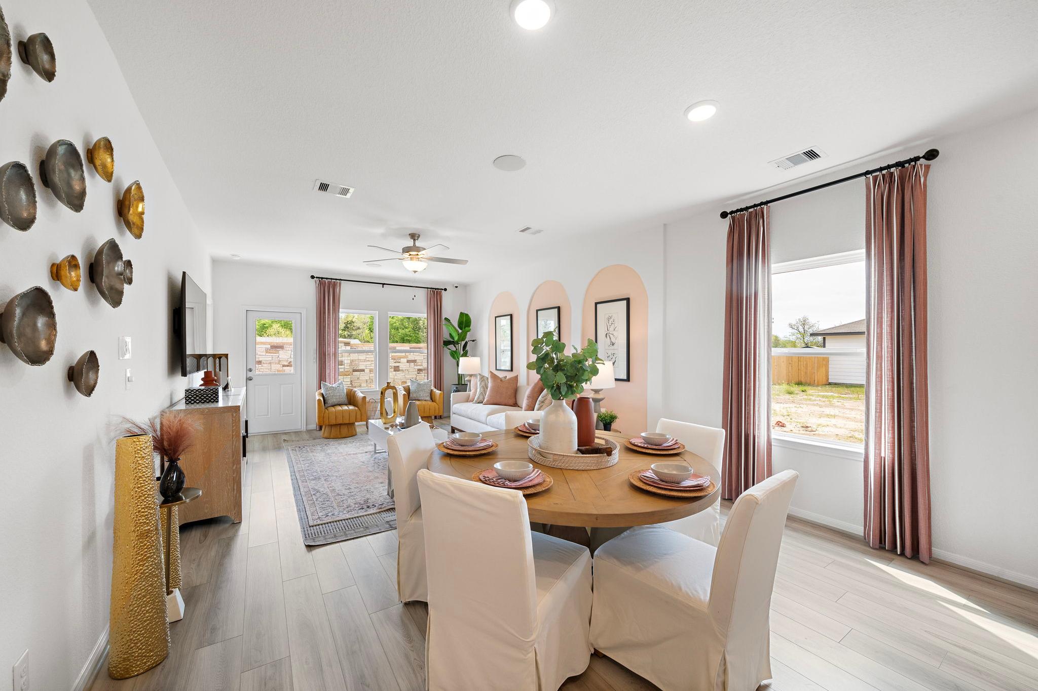 Spacious open-concept dining area in Davidson Homes at The Villages at WestPointe Dayton Texas with round table hardwood floors and pink arched walls