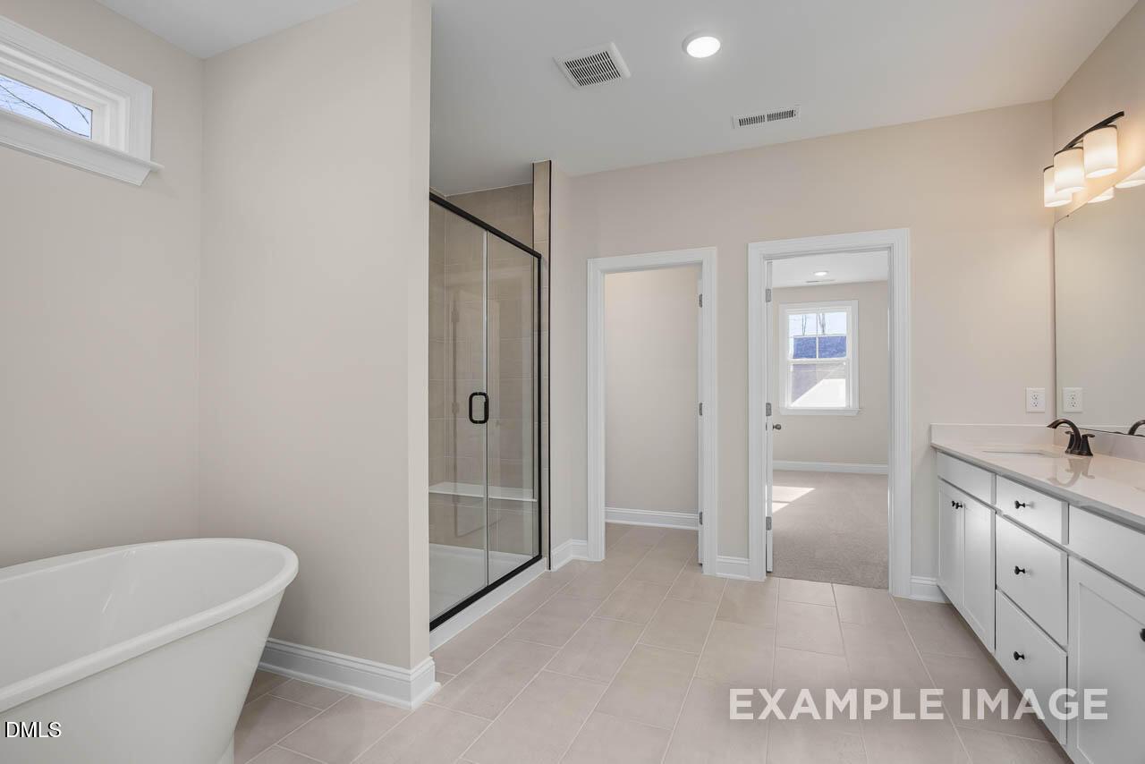 Luxurious master bathroom with freestanding tub, glass shower, double vanity in The Crawford D by Davidson Homes, Angier, NC