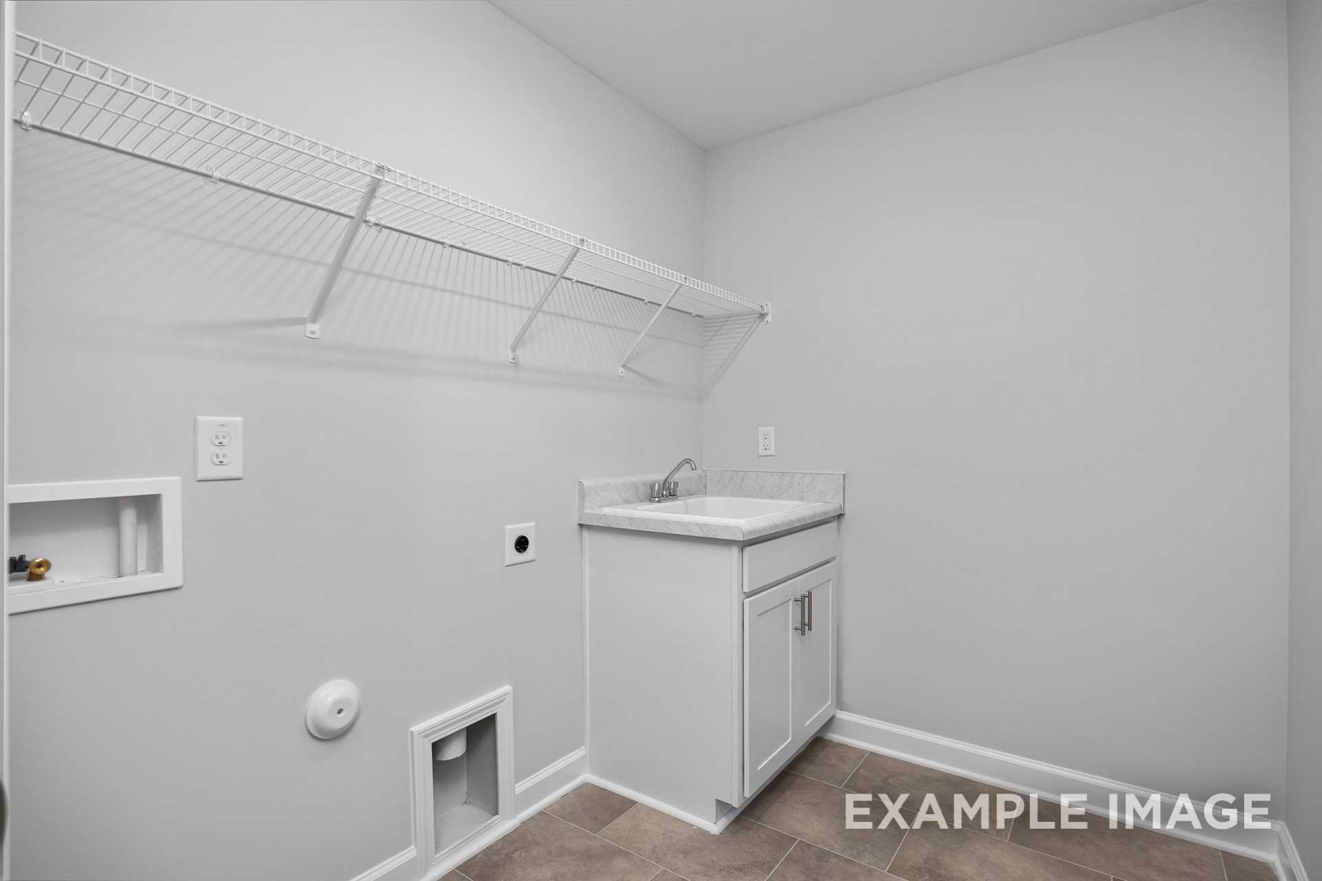 Spacious laundry room in The Preston B with white utility sink, cabinetry, built-in shelving, and dryer vent