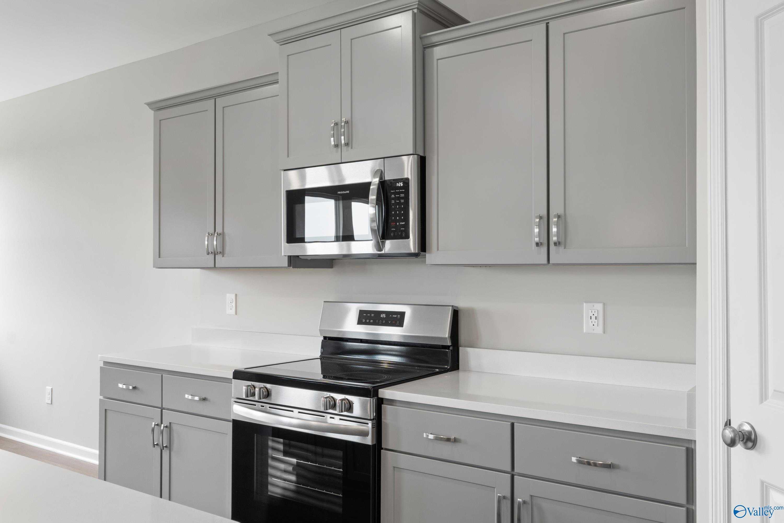 Modern gray shaker cabinets with stainless steel microwave and range in The Dorado kitchen, Davidson Homes Athens Alabama
