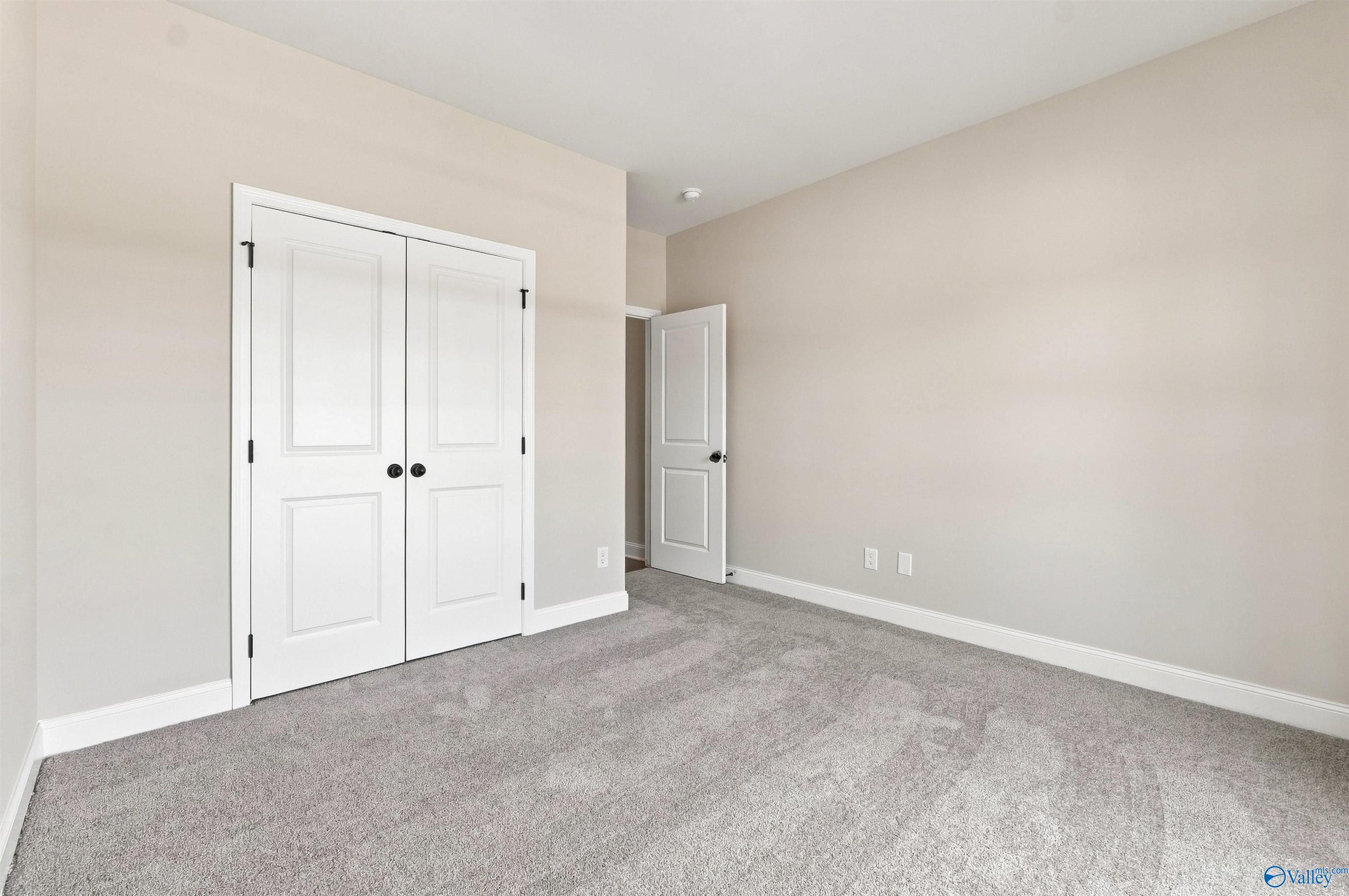 Spacious carpeted bedroom with white double-door closet in Davidson Homes The Everett B, Wood Trail, Toney, Alabama