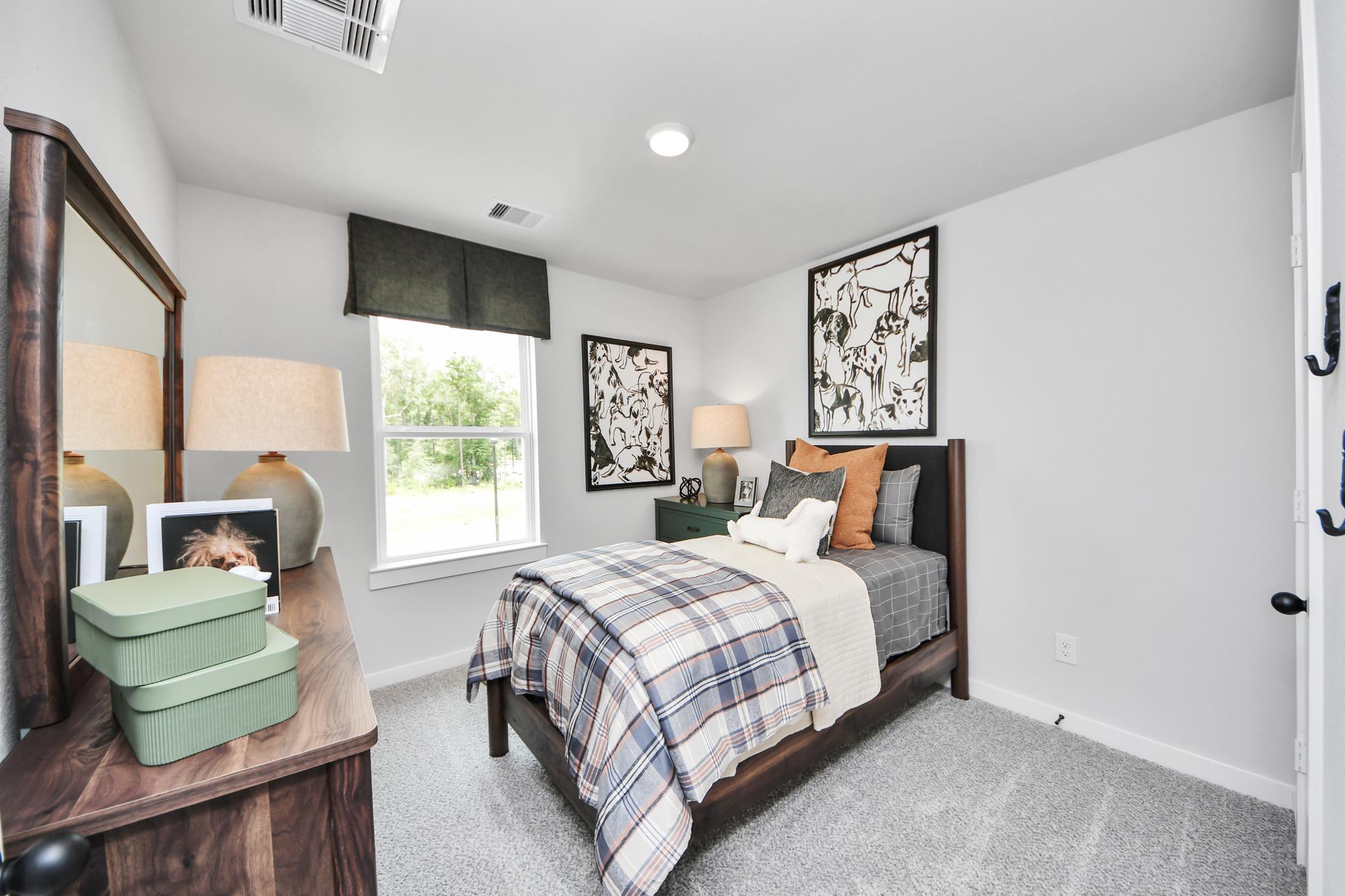 Cozy bedroom with plaid bedding at Robins Landing in Houston, TX by Davidson Homes featuring a modern wooden bed frame.