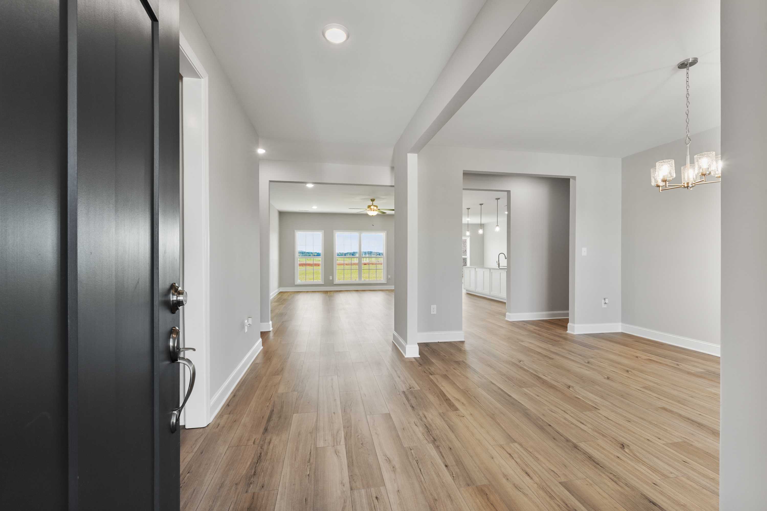 Spacious entry foyer in The Valencia home design with open layout, hardwood floors, and large windows overlooking fields