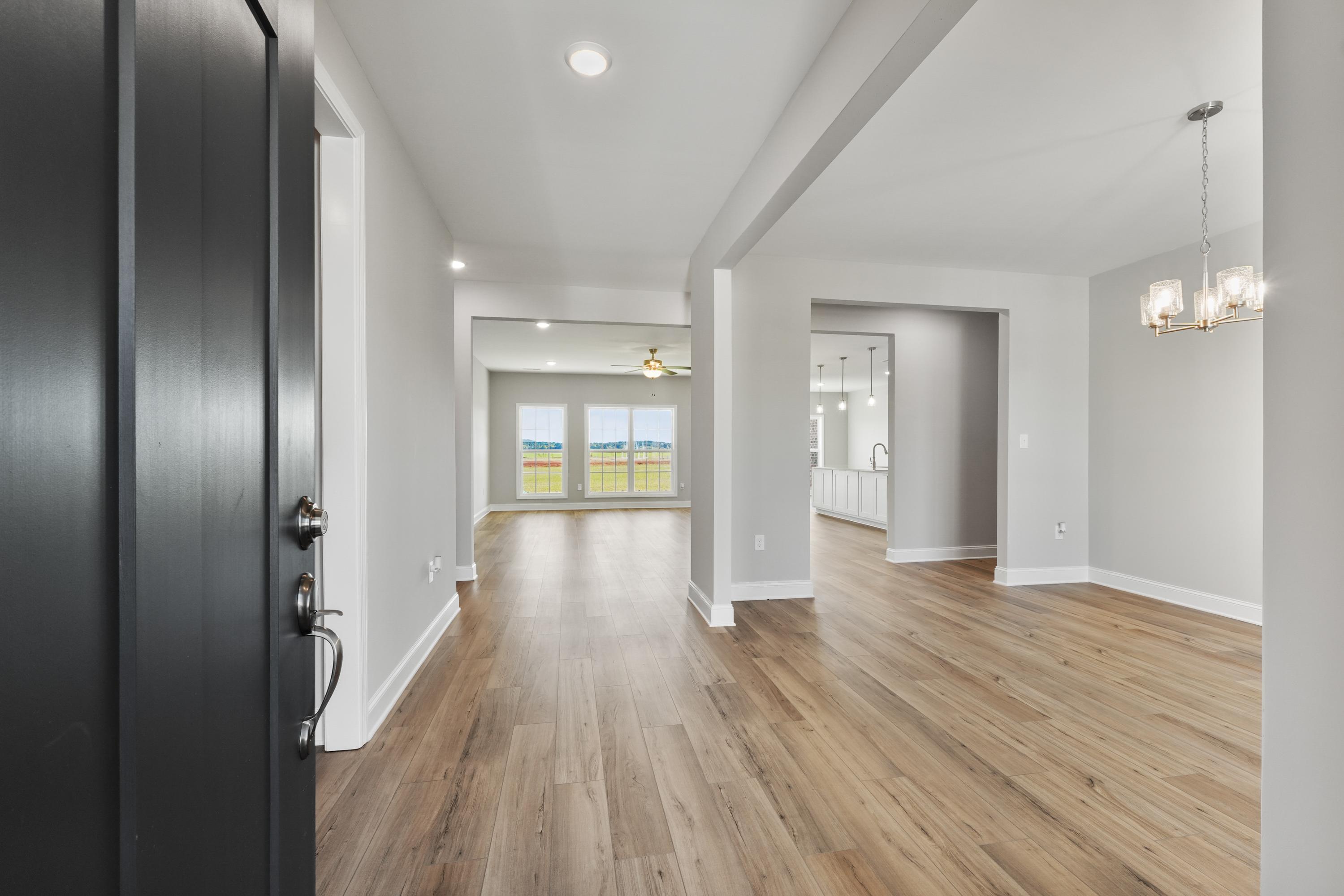 Spacious entry foyer in The Valencia home design with open layout, hardwood floors, and large windows overlooking fields