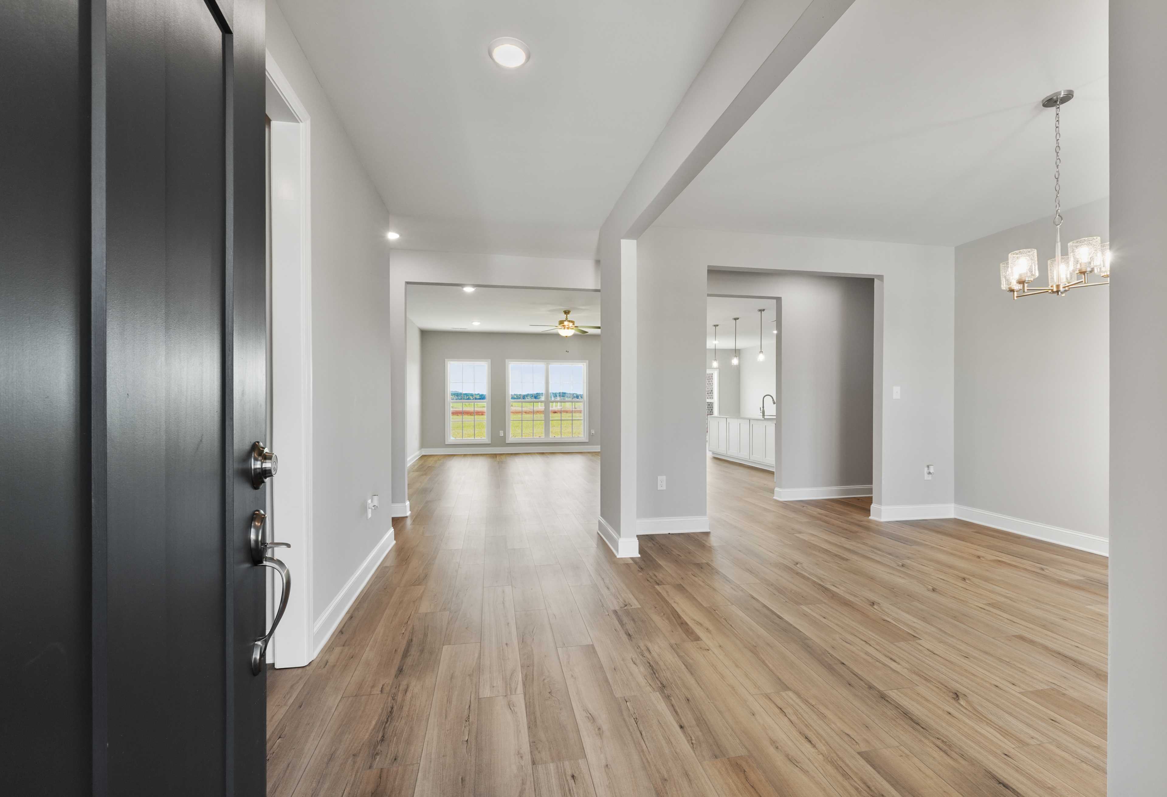 Spacious entry foyer in The Valencia home design with open layout, hardwood floors, and large windows overlooking fields