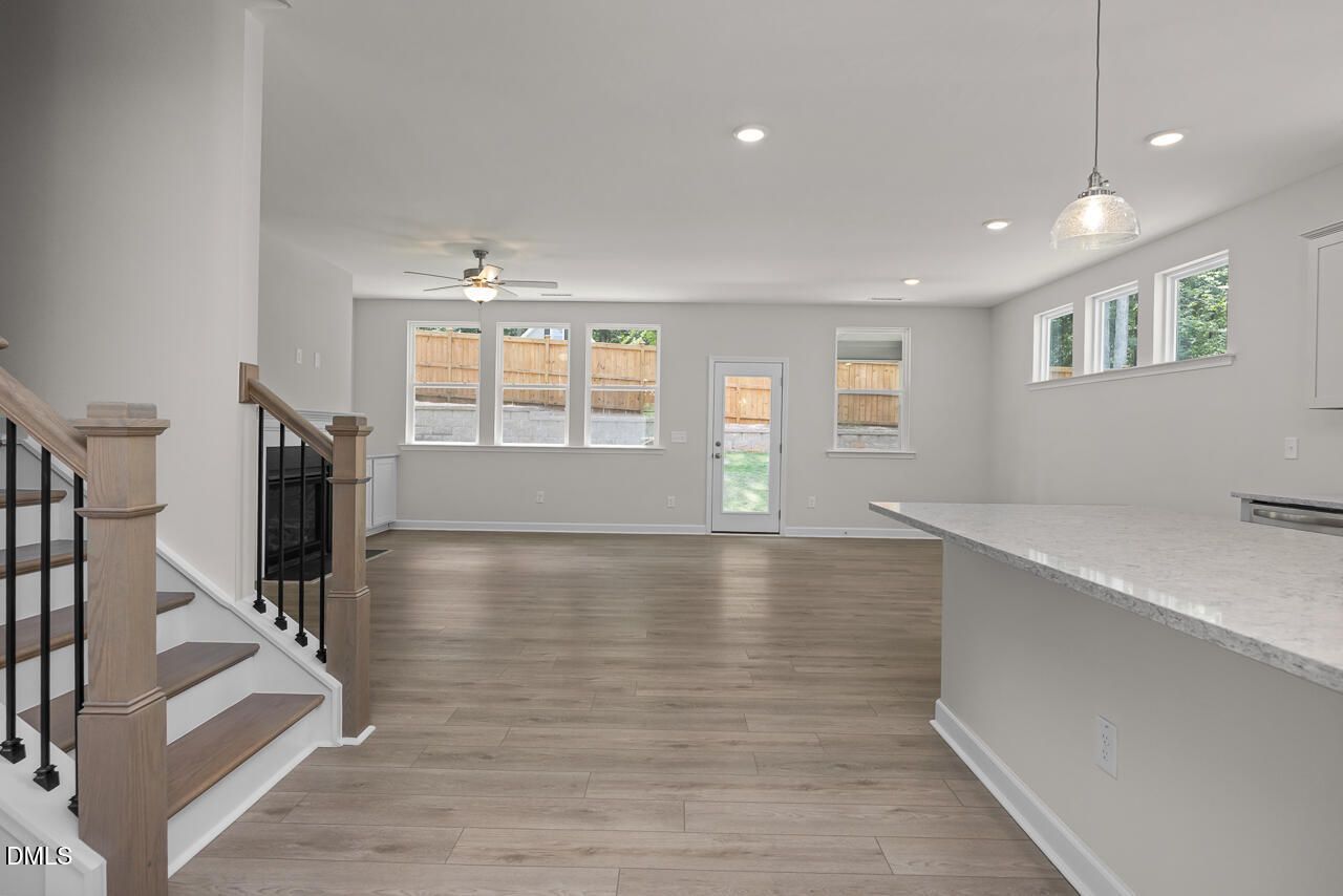 Open-concept living room and kitchen with light wood floors in The Ashport G floor plan, Sage on North Main, Wake Forest.