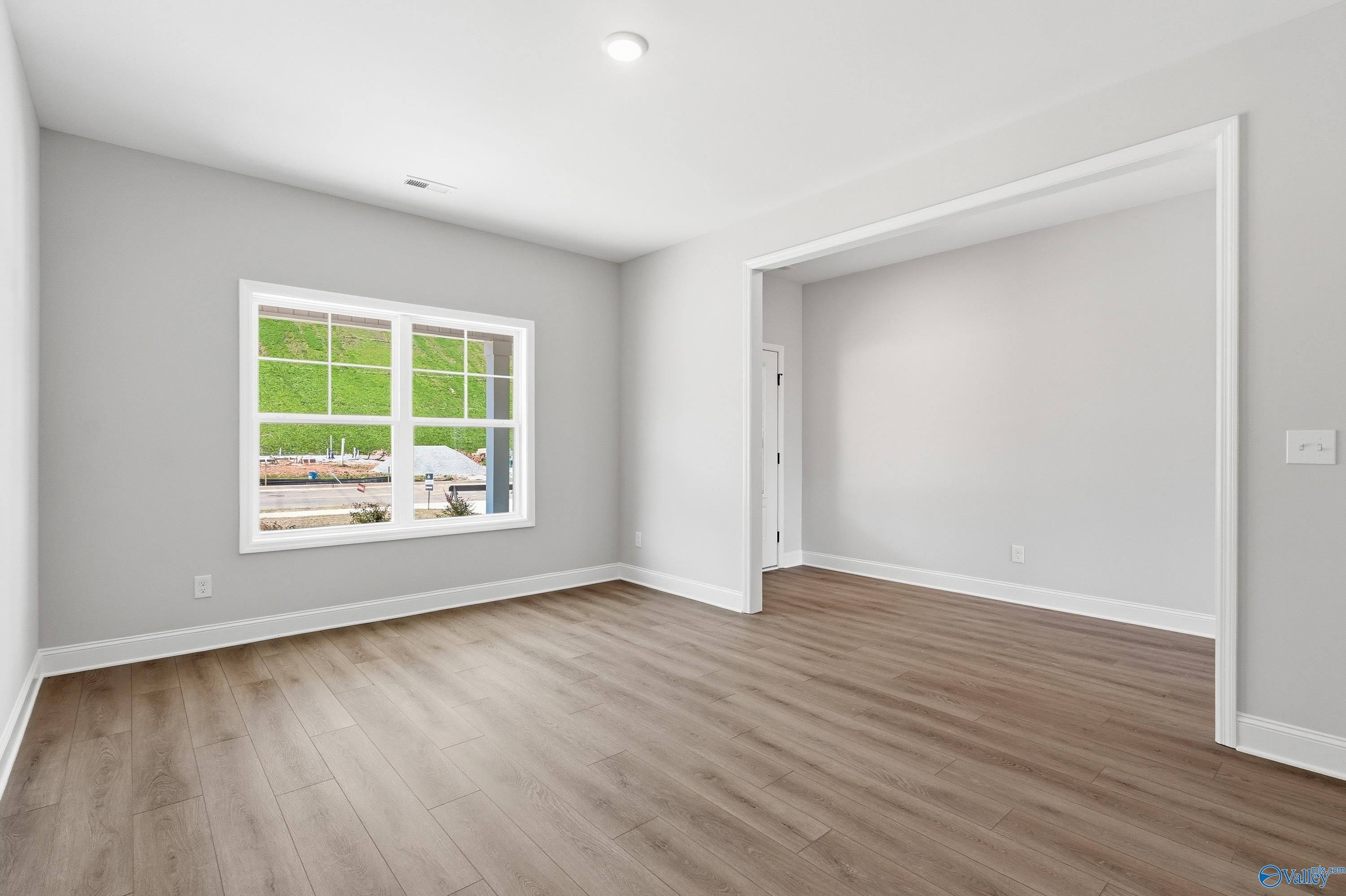 Bright bedroom with large window overlooking greenery, light gray walls, hardwood floors in Davidson Homes Chelsea D, Cullman AL