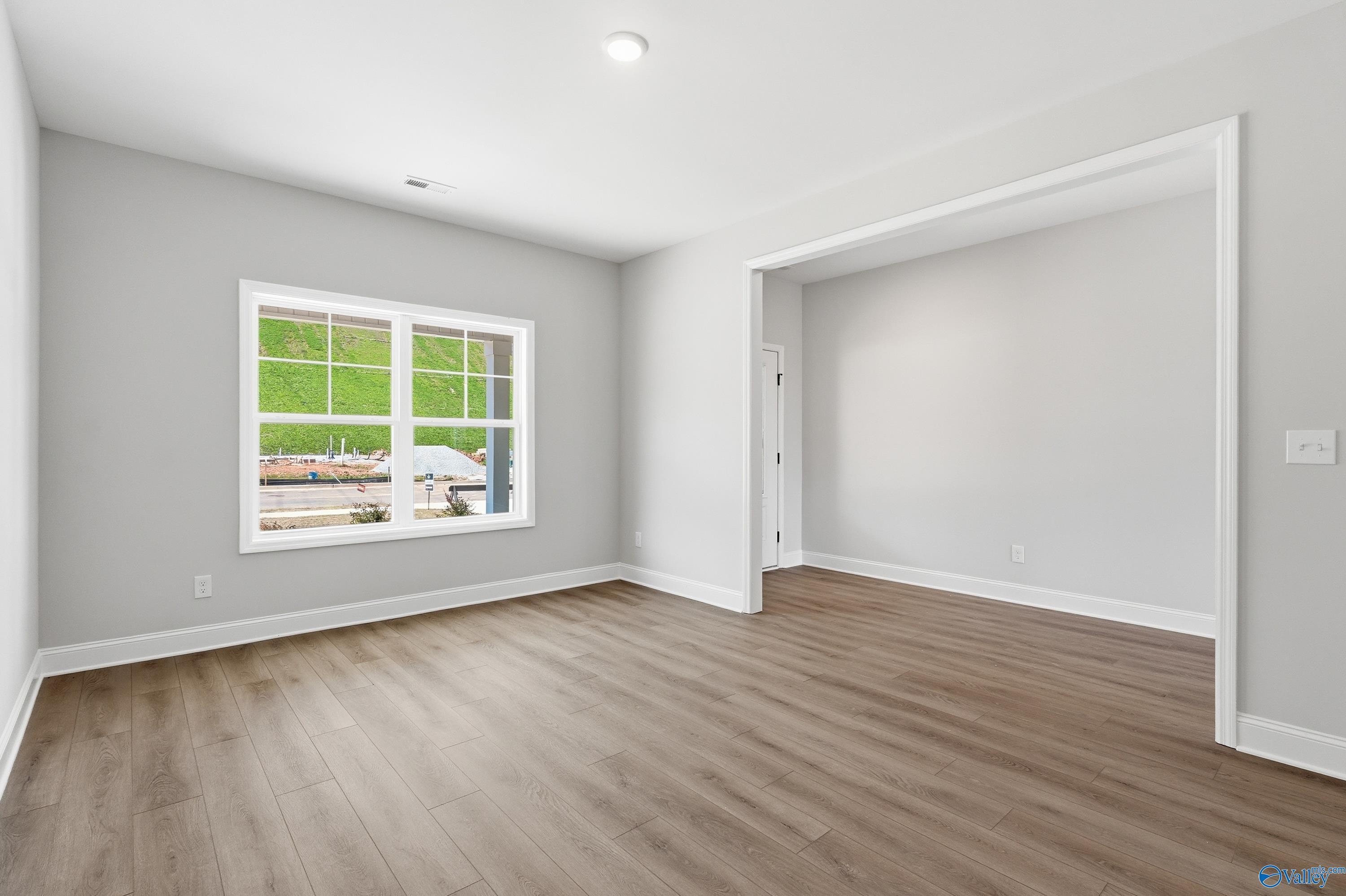 Bright bedroom with large window overlooking greenery, light gray walls, hardwood floors in Davidson Homes Chelsea D, Cullman AL