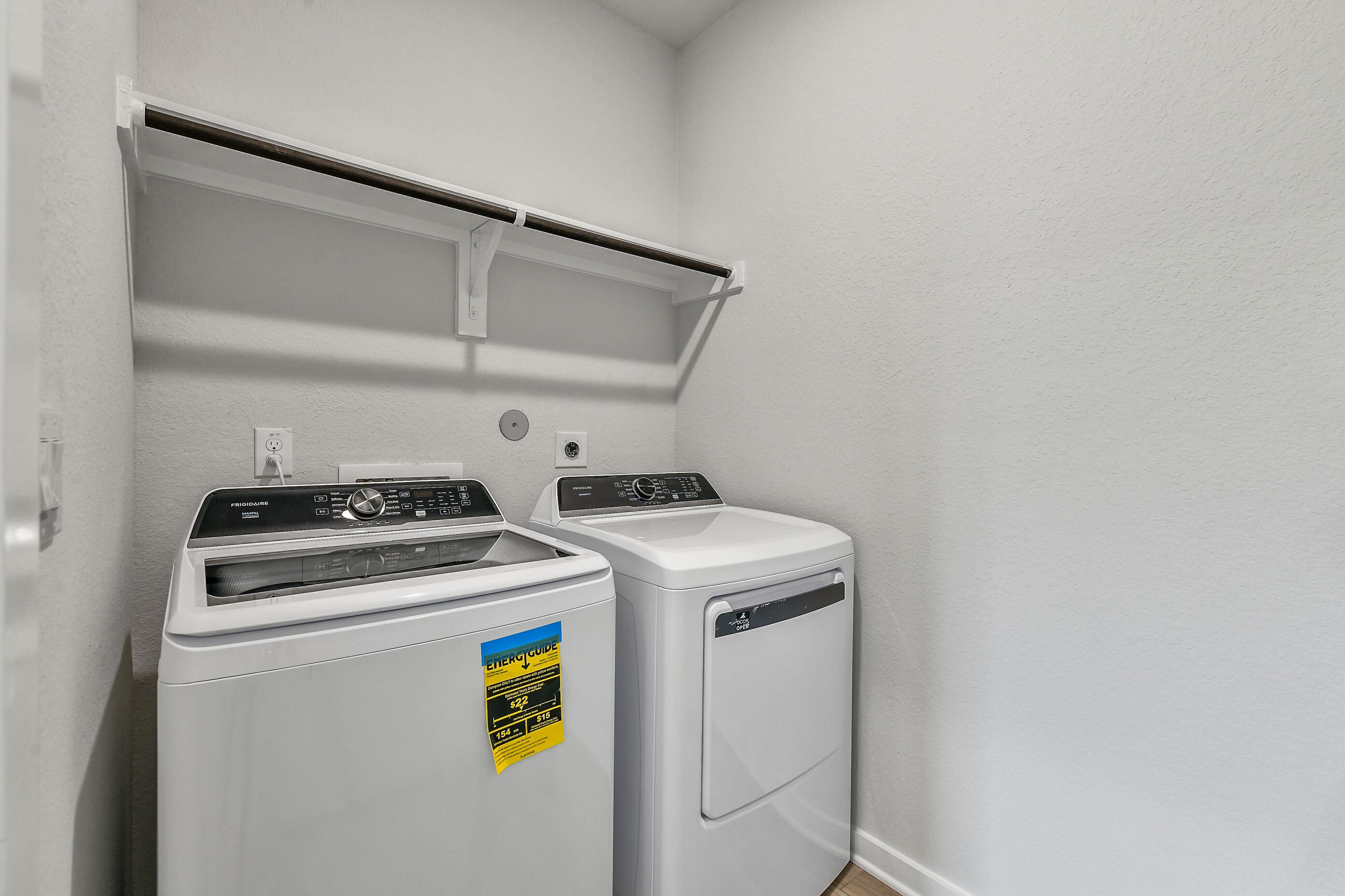 Modern laundry room with Frigidaire washer dryer and built-in shelves in Davidson Homes The Colorado G, Windmill Estates, Magnolia, TX