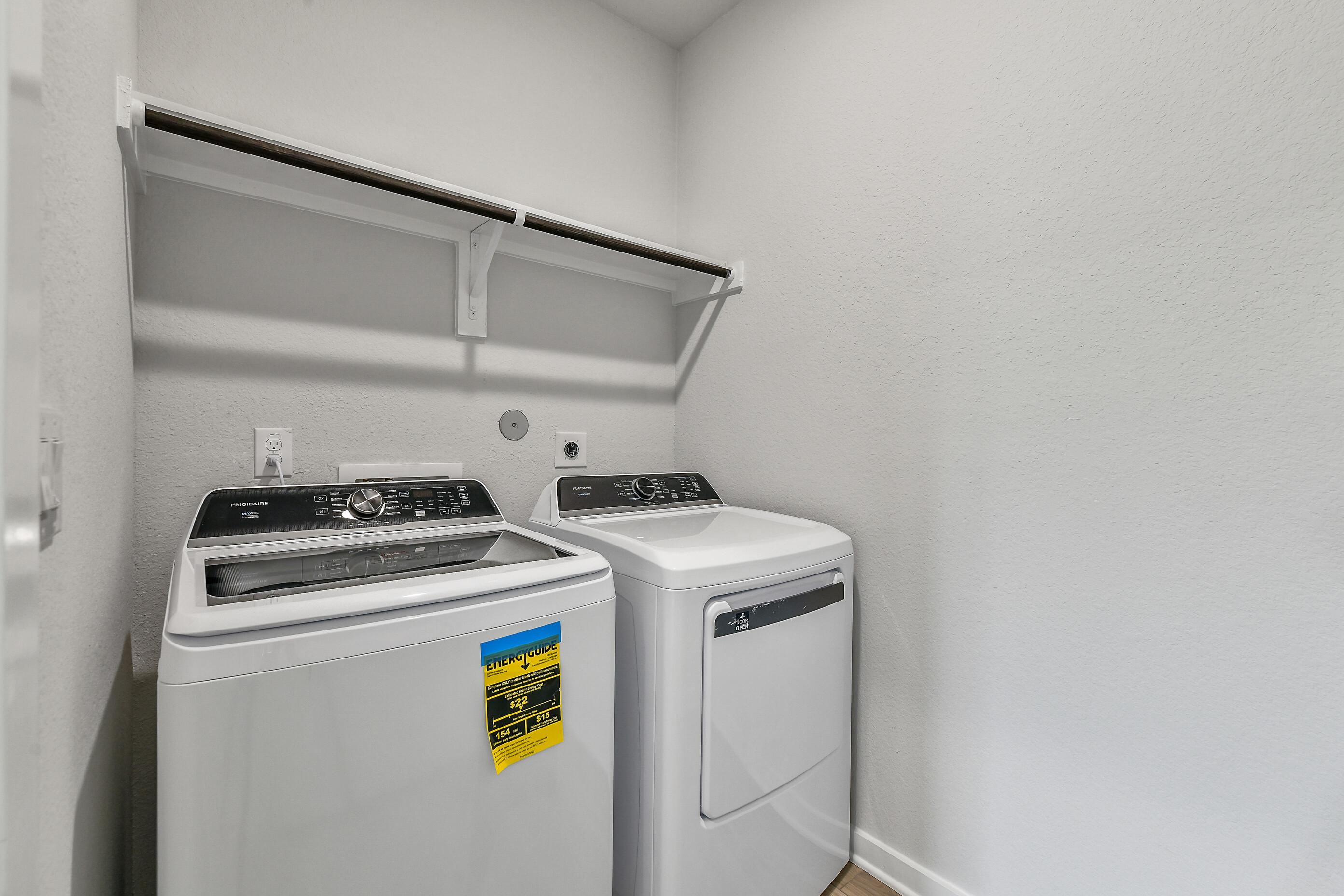 Modern laundry room with Frigidaire washer dryer and built-in shelves in Davidson Homes The Colorado G, Windmill Estates, Magnolia, TX
