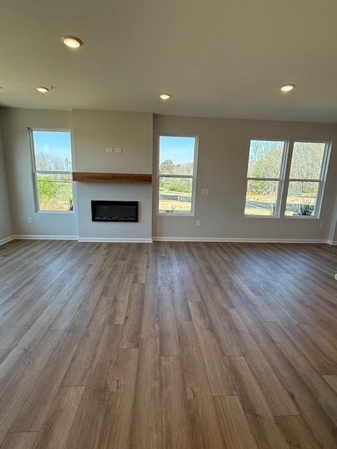Spacious living room with modern fireplace and wood-look flooring in The Durham D floor plan at Hemingway, Cumming, GA.