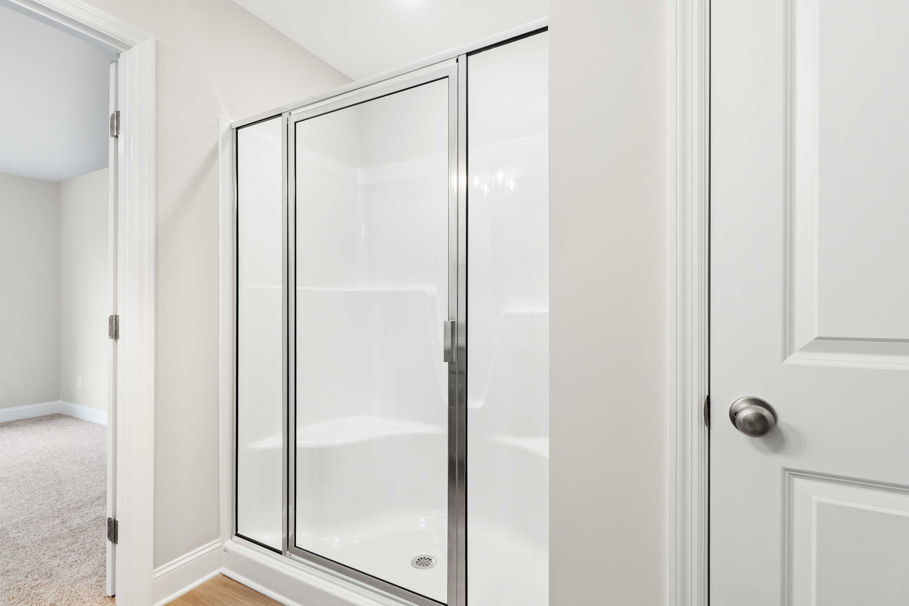 Spacious master bathroom shower in The Asheville home design with frameless glass doors and white subway tile