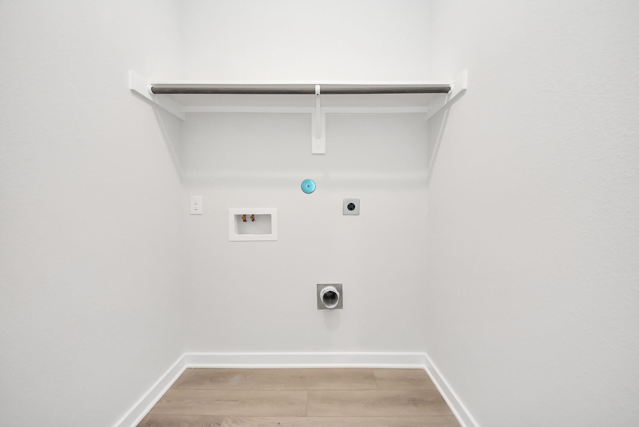 Utility room with washer and dryer connections and overhead shelving in The Blanco F floor plan at Spring Branch Crossing.