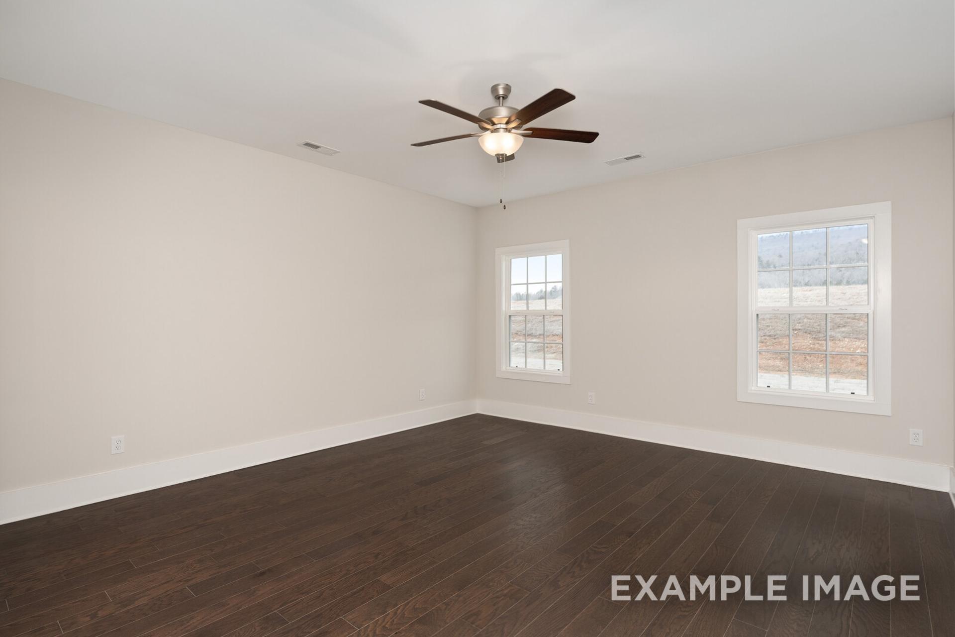 Spacious empty bedroom in The Rockford home design with beige walls, hardwood floors, ceiling fan, and double windows