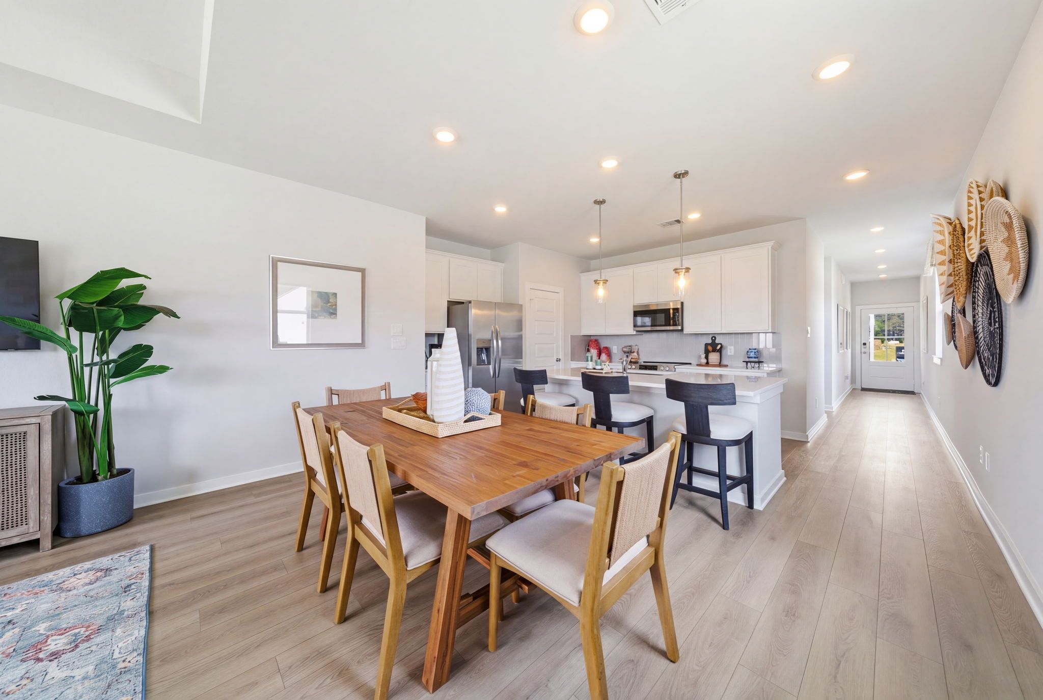 Spacious open-concept kitchen dining area at Spring Branch Crossing Conroe TX with white shaker cabinets wooden table bar island and plants