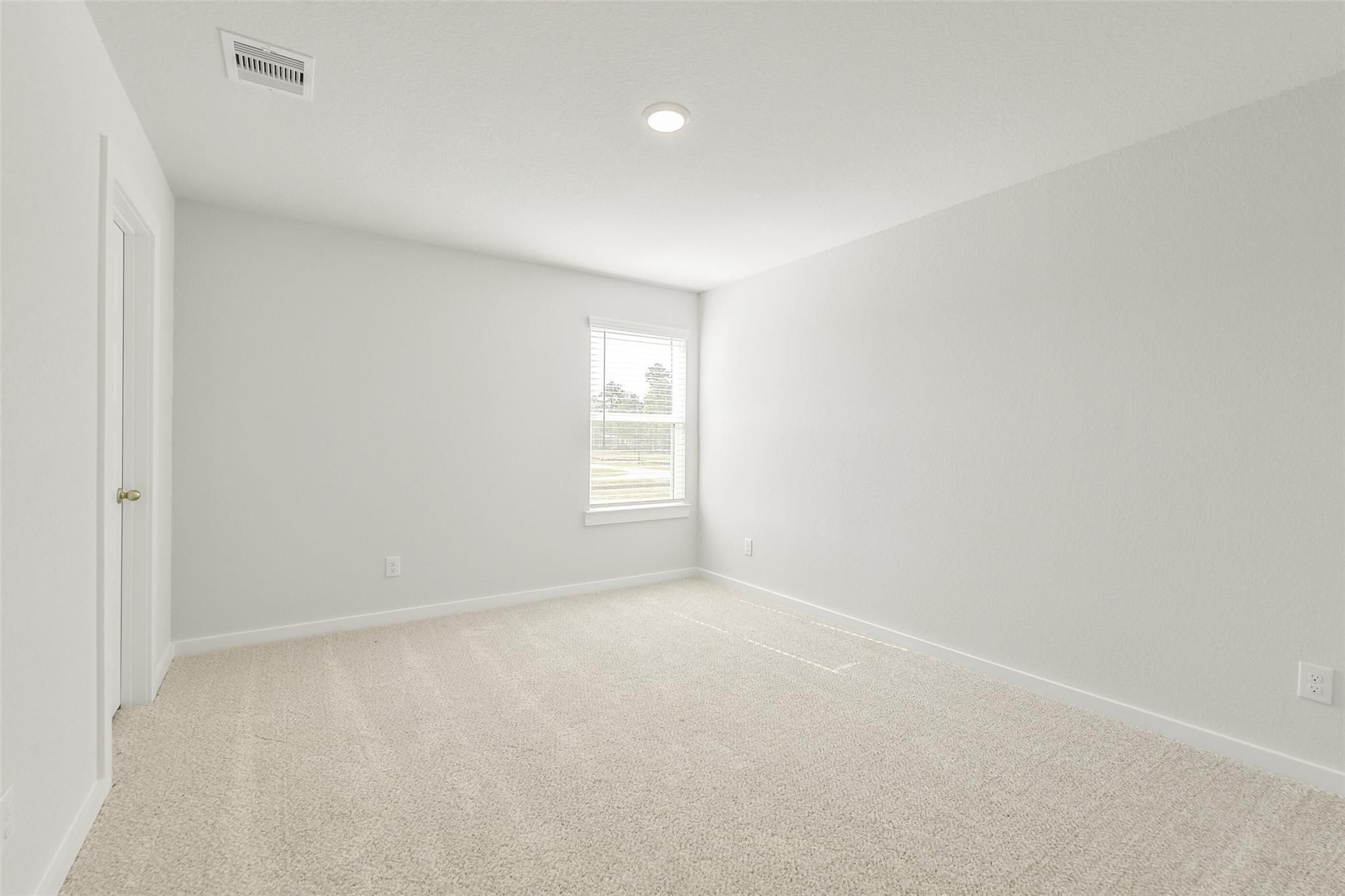Empty secondary bedroom with light gray walls, beige carpet, large window in Davidson Homes The San Marcos E, Cleveland, Texas