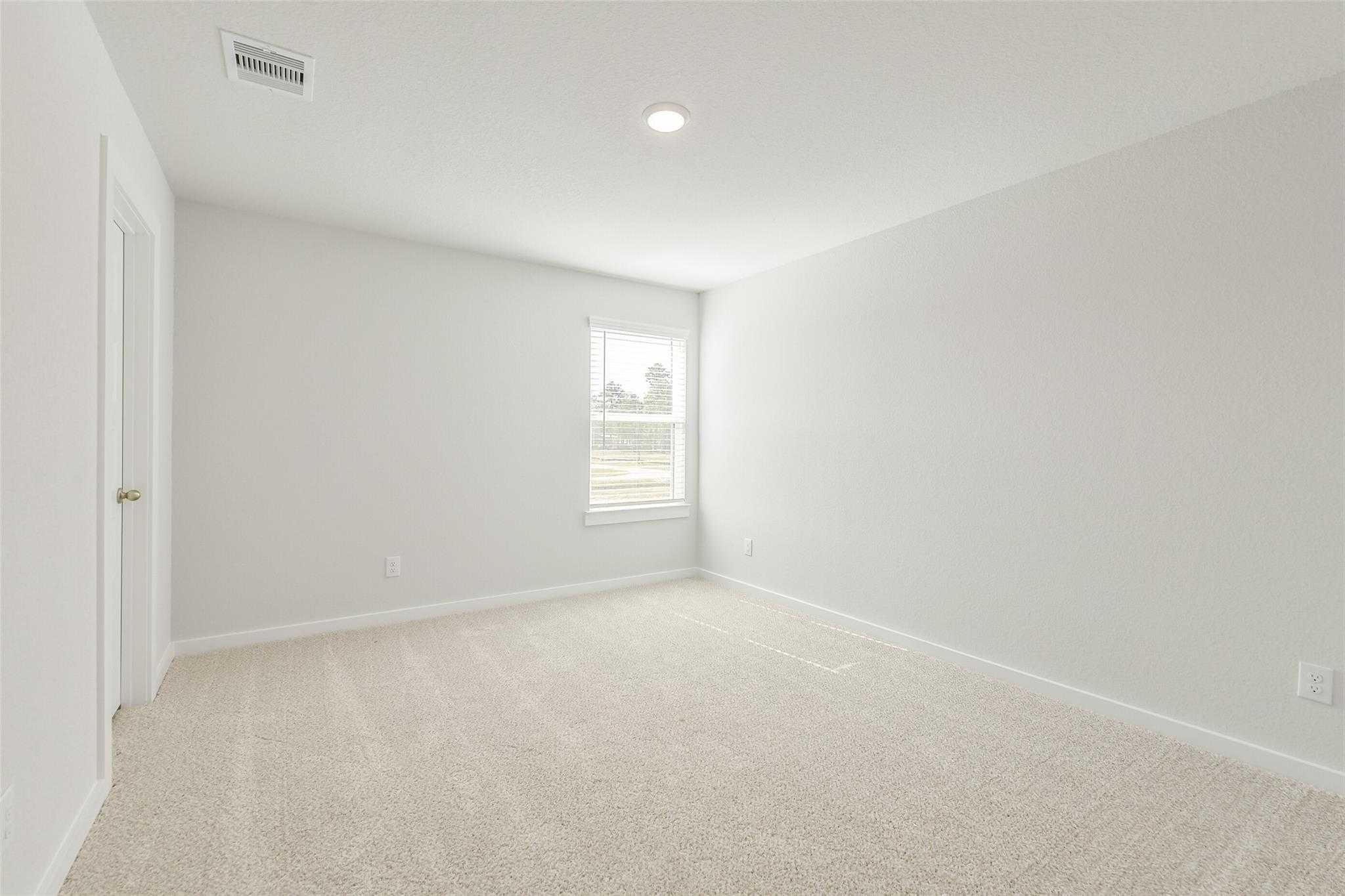 Empty secondary bedroom with light gray walls, beige carpet, large window in Davidson Homes The San Marcos E, Cleveland, Texas