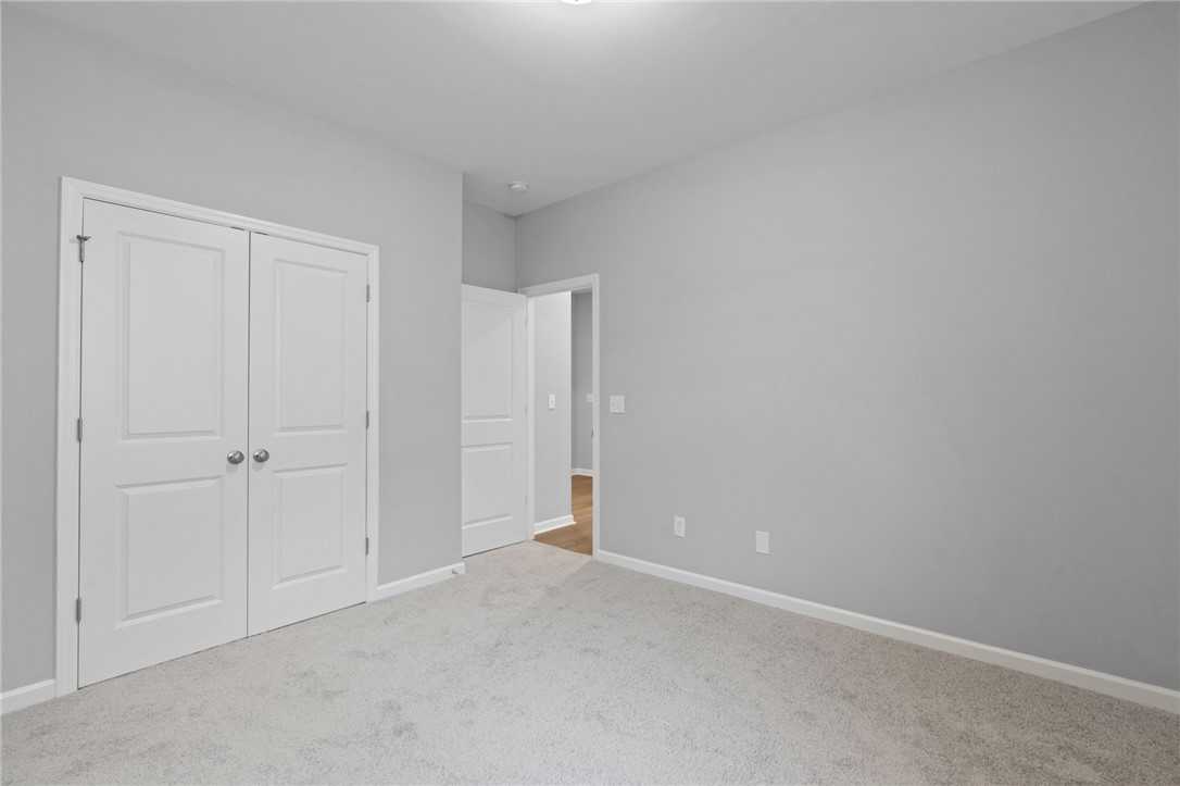 Spacious secondary bedroom with gray walls, white double closet doors, carpeted floor in Davidson Homes The Luna B, Opelika