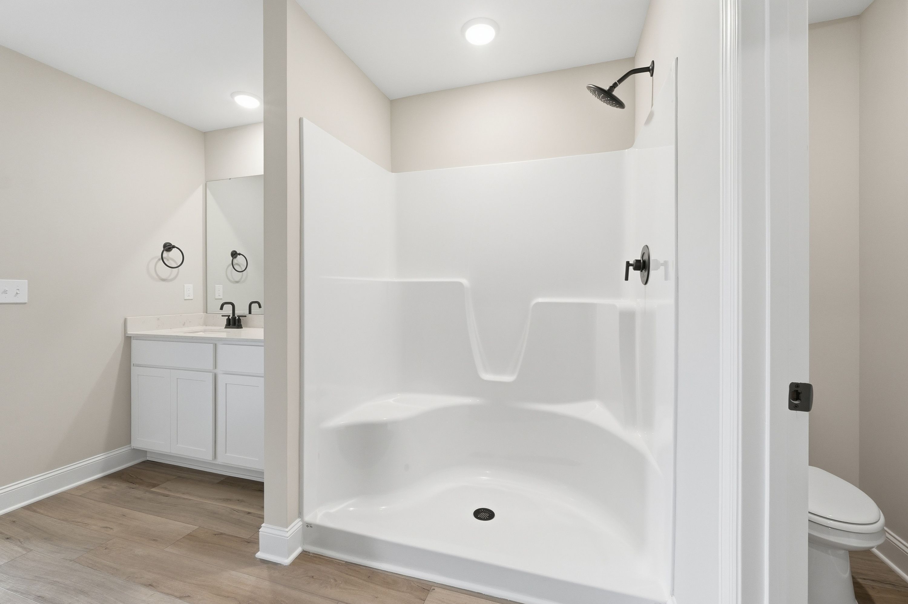 Modern master bathroom in The Daphne V featuring walk-in shower, double vanity, and sleek white fixtures