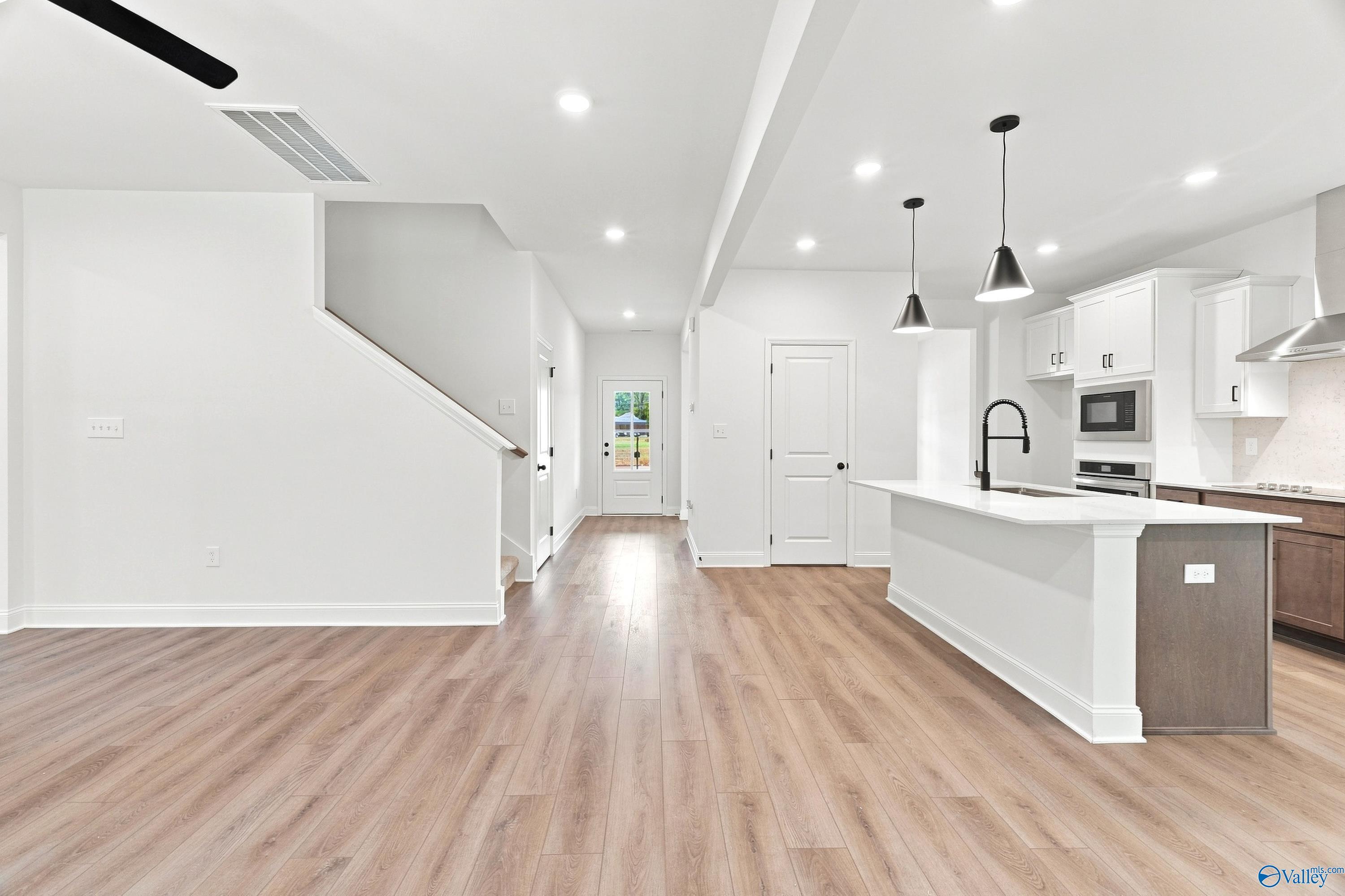 Open-concept kitchen and living area with wood floors in The Shelby B floor plan by Davidson Homes in Huntsville, Alabama.