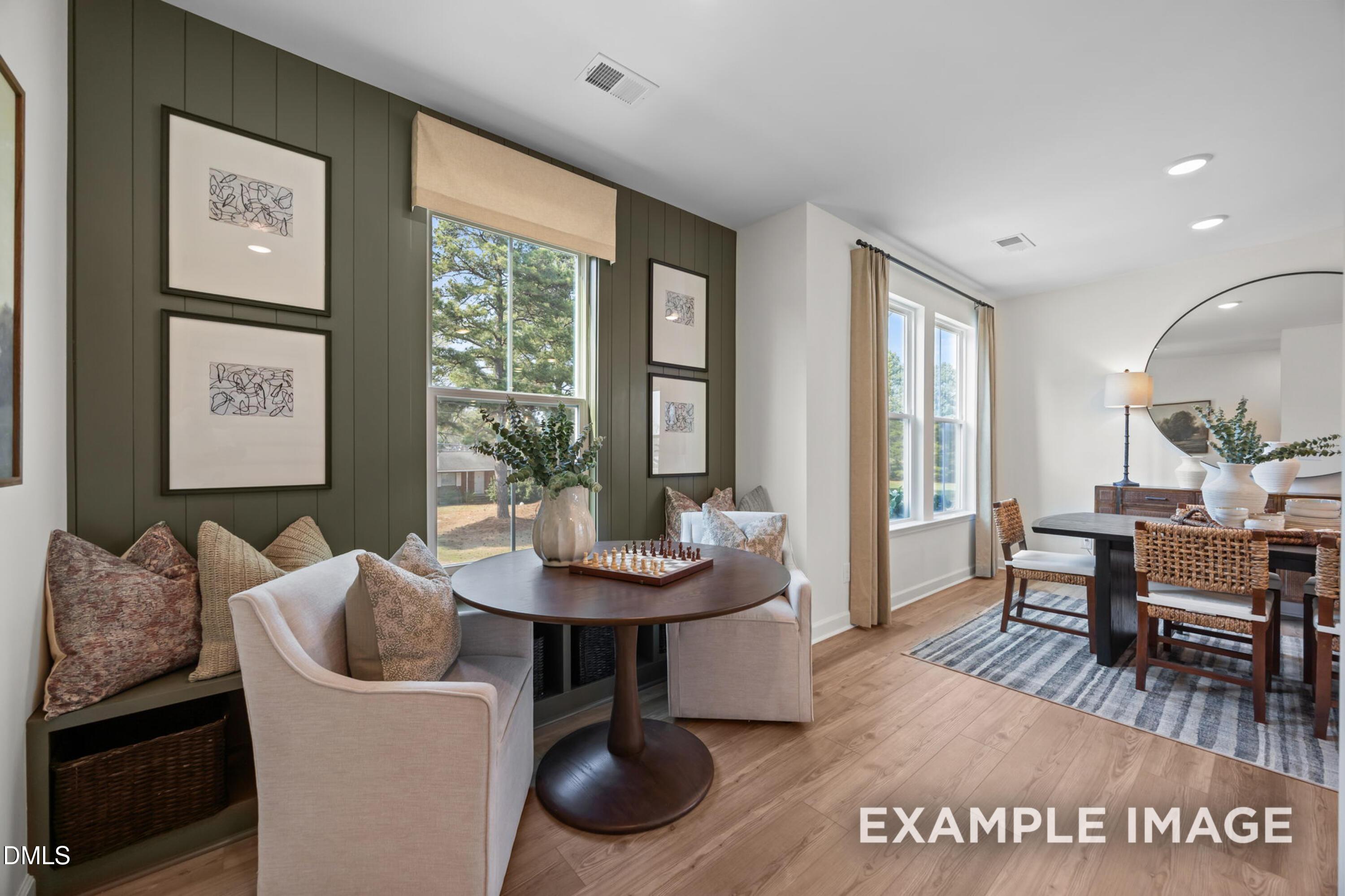 Cozy built-in window bench with round chess table, plush pillows, and tree views in Davidson Homes The Mitchell, Knightdale, NC
