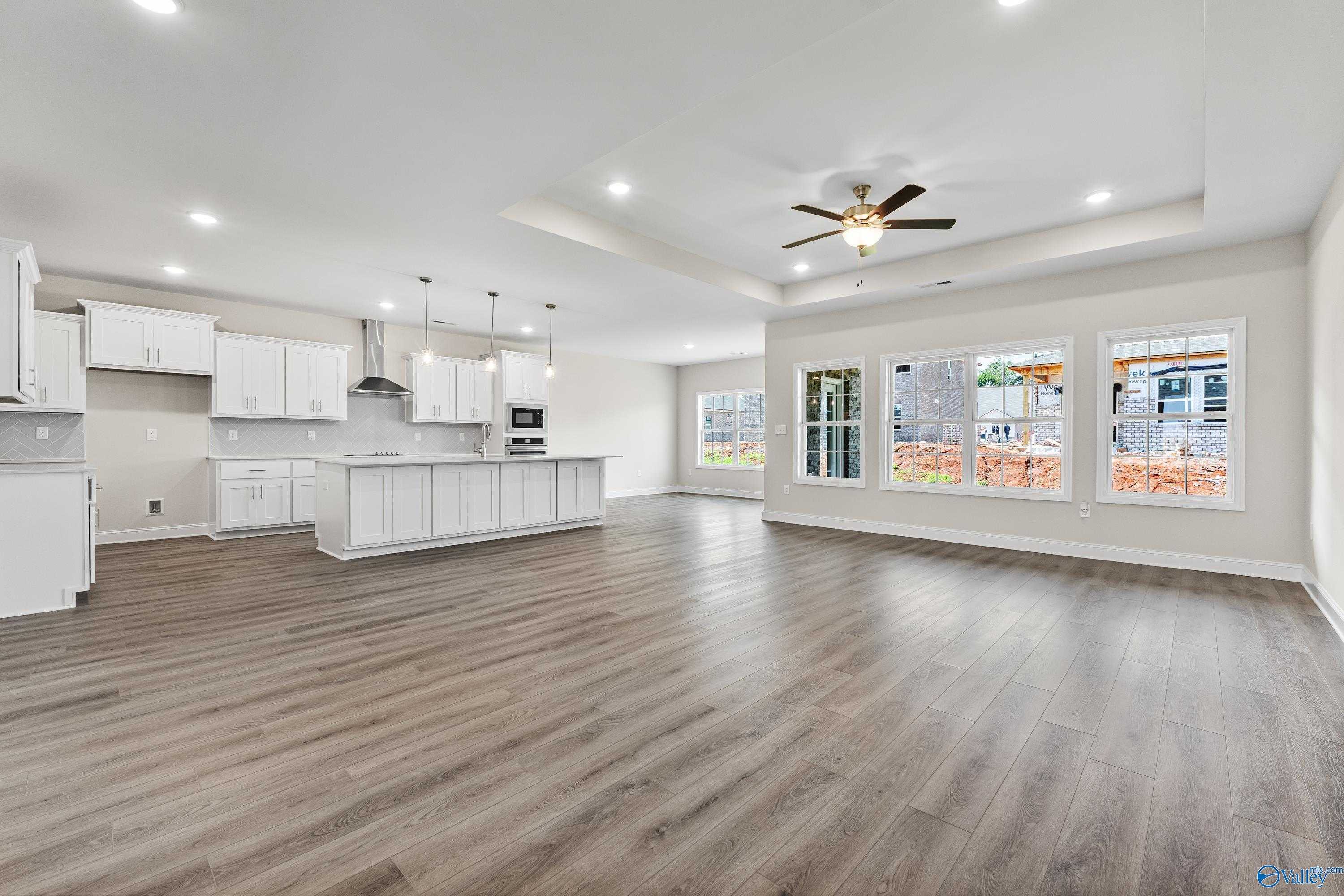Open-concept kitchen with white shaker cabinets, granite island, pendant lights, and large windows in Davidson Homes The Finleigh, Toney, Alabama