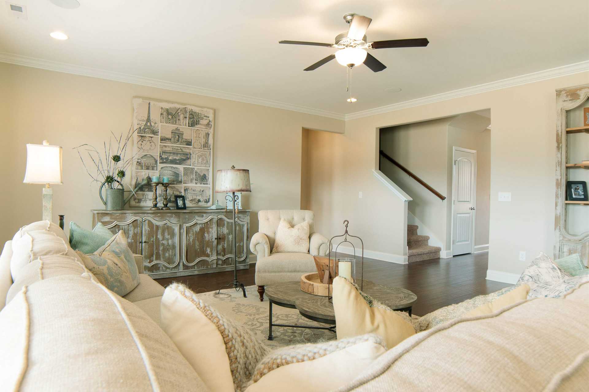 Spacious open-concept living room at The Dairy at Oak Grove in South Huntsville Alabama with cream sofa, wooden floors, and staircase